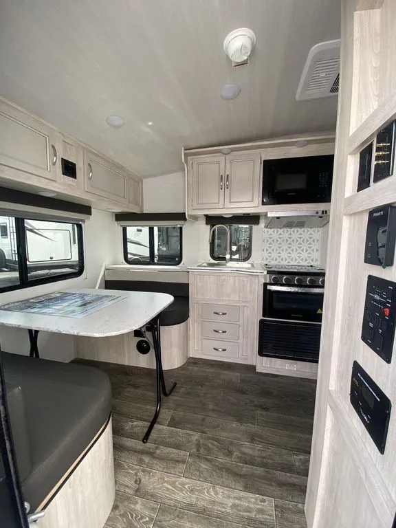2026 Gulf Stream Vista Cruiser 19ERD — Travel trailer kitchen with sink, range, microwave, cabinetry, and adjacent dinette seating