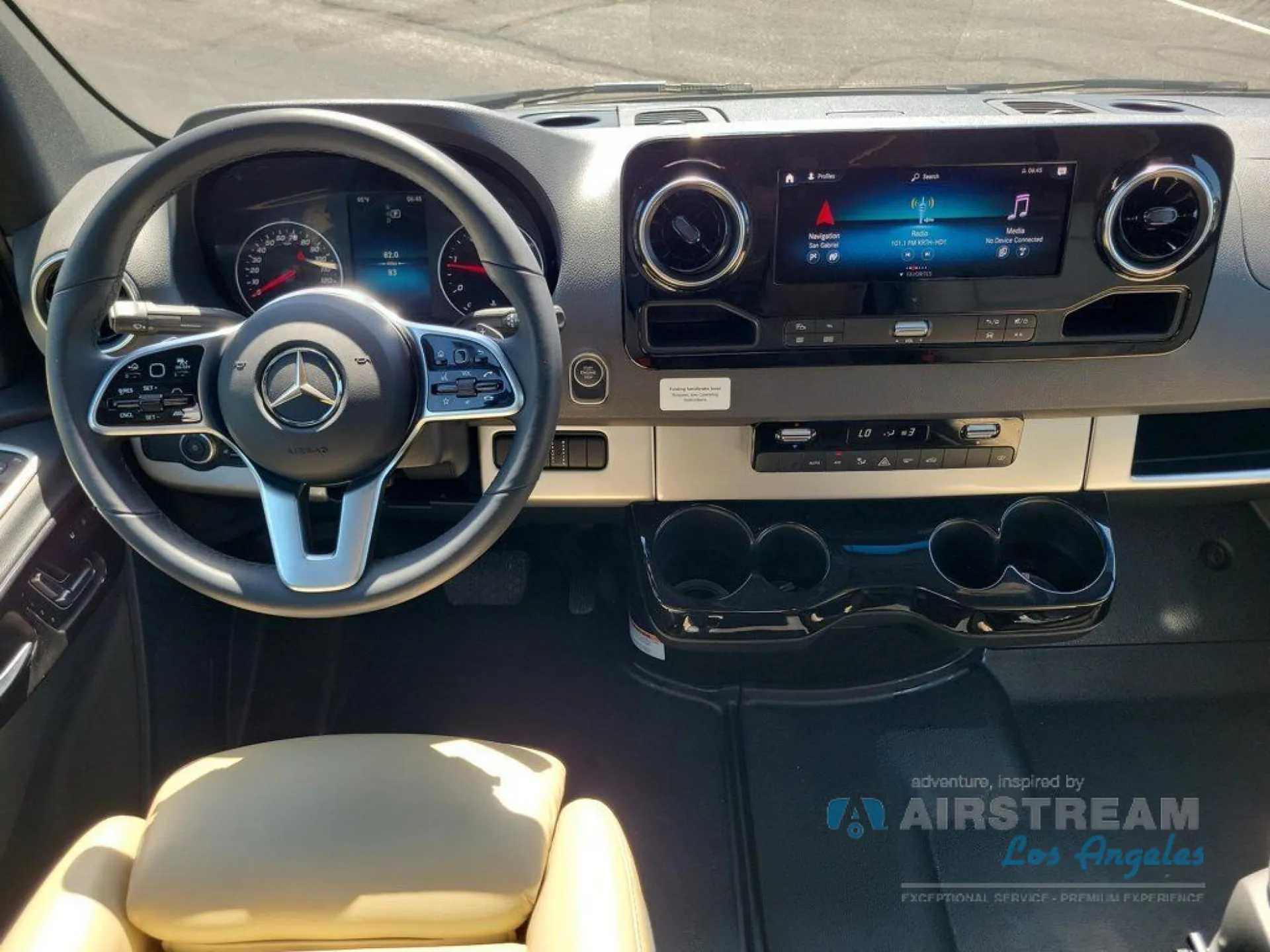 2026 Airstream Atlas Murphy Suite — Front-facing Class B van dashboard with steering wheel, instrument cluster, infotainment screen, climate controls, and cupholders