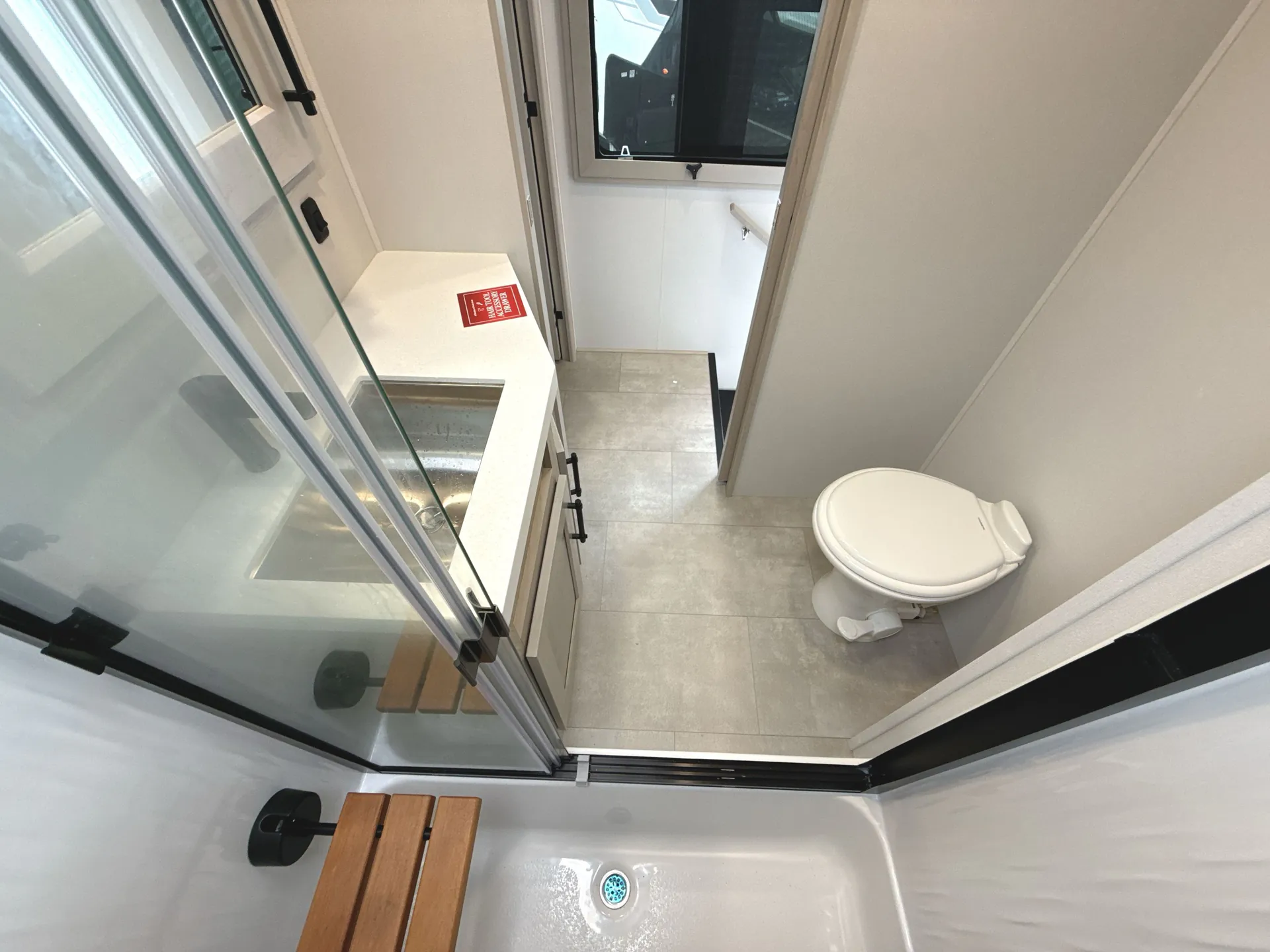2026 Grand Design Solitude 391DL — Bathroom with glass shower enclosure, bathtub, vanity sink, toilet, window, and connecting doorway