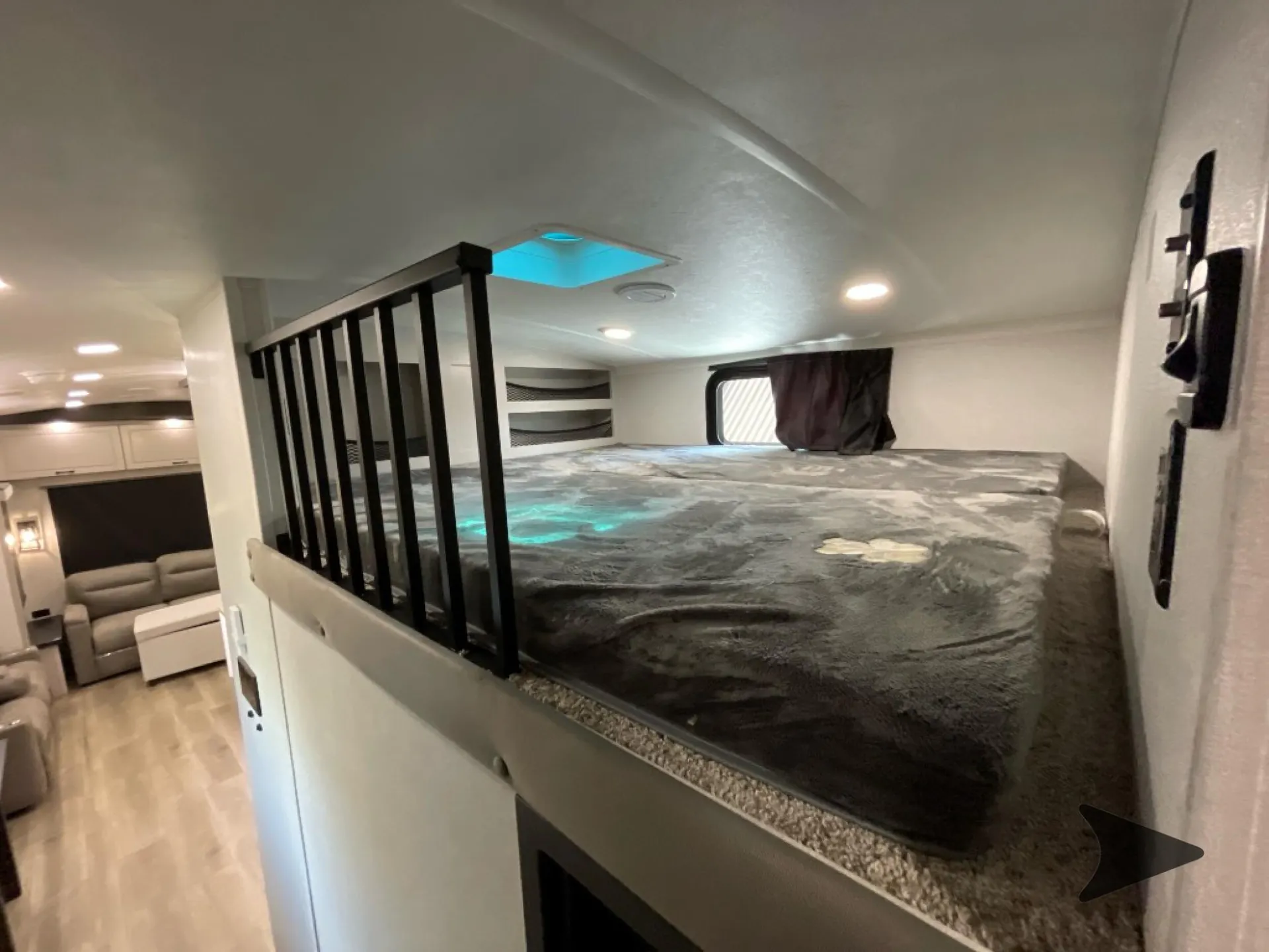 2026 Jayco North Point 377RLBH — Elevated over-cab bed with guardrail above a visible lounge containing sofas and a table