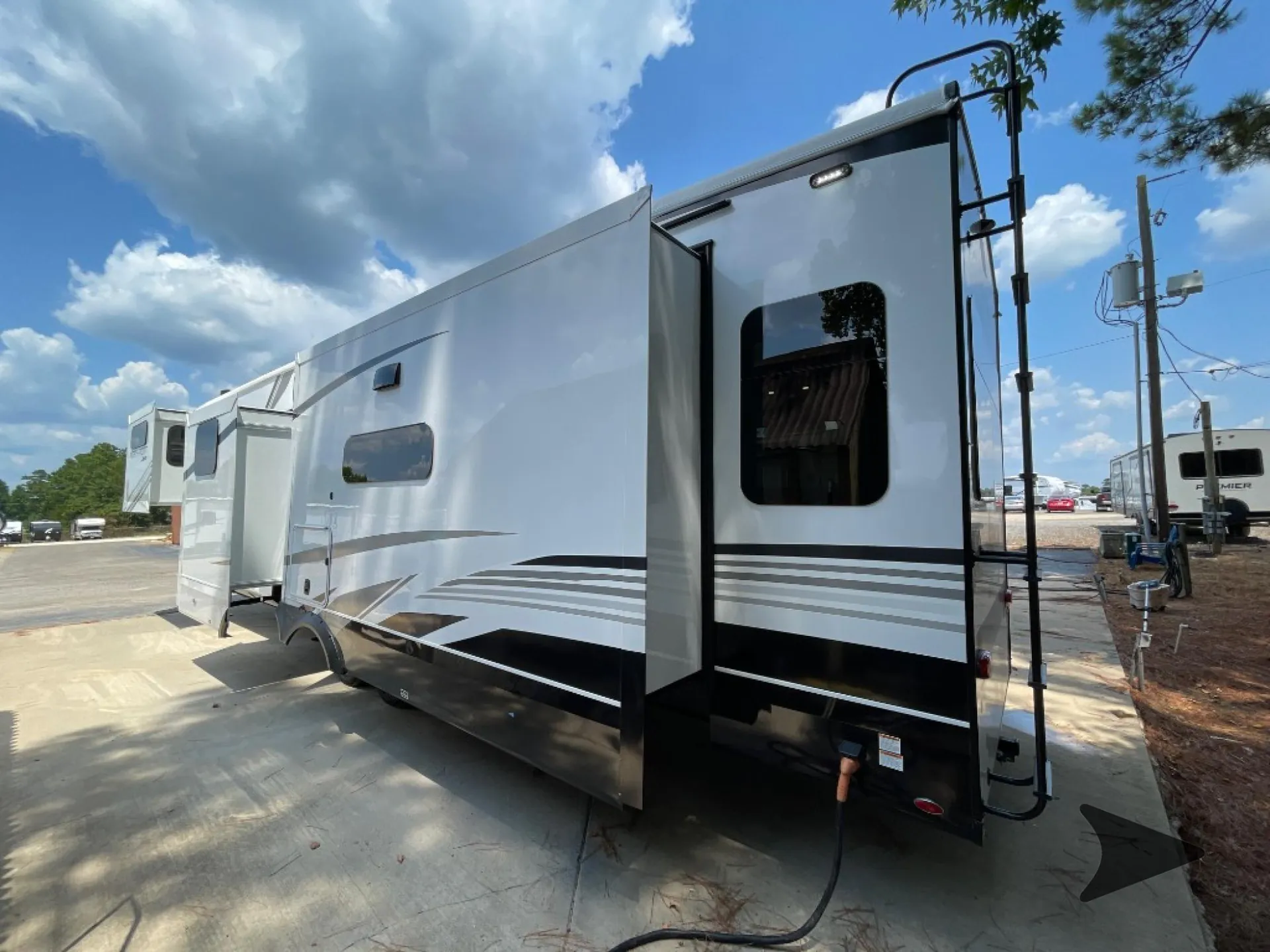 2026 Jayco North Point 377RLBH — Rear-side exterior photograph visibly shows the RV body, rear ladder, slide-outs, and hookups