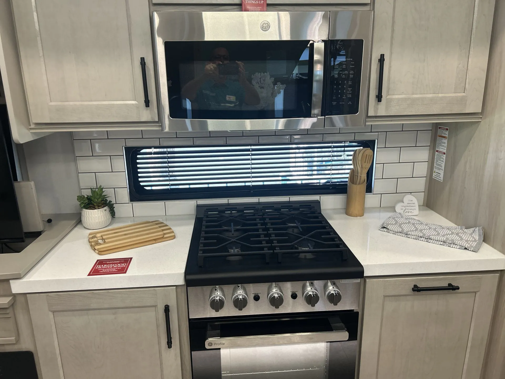 2026 Grand Design Solitude 391DL — Fifth wheel kitchen with gas range, oven, microwave, countertop workspace, cabinets, and backsplash