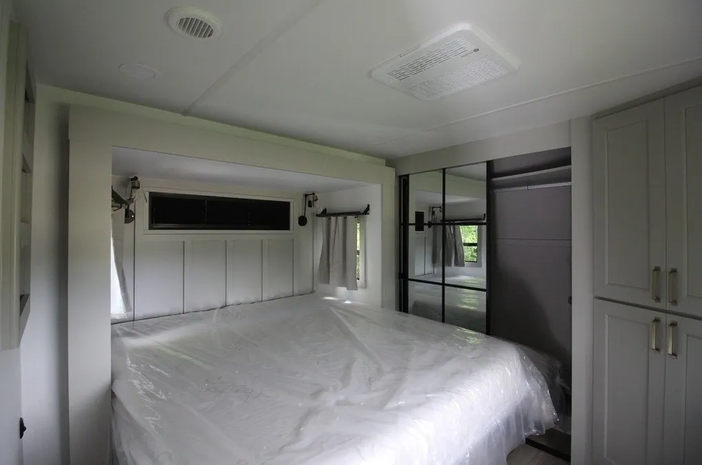 2025 Brinkley Model G 3250 — Main bedroom with a plastic-wrapped bed, mirrored wardrobe doors, and built-in cabinets