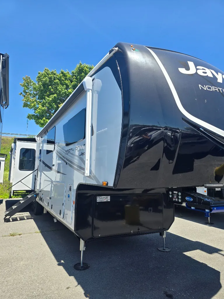 2026 Jayco North Point 377RLBH — The exterior front and side of a Jayco North Point fifth-wheel RV, including slides, hitch area, and leveling legs