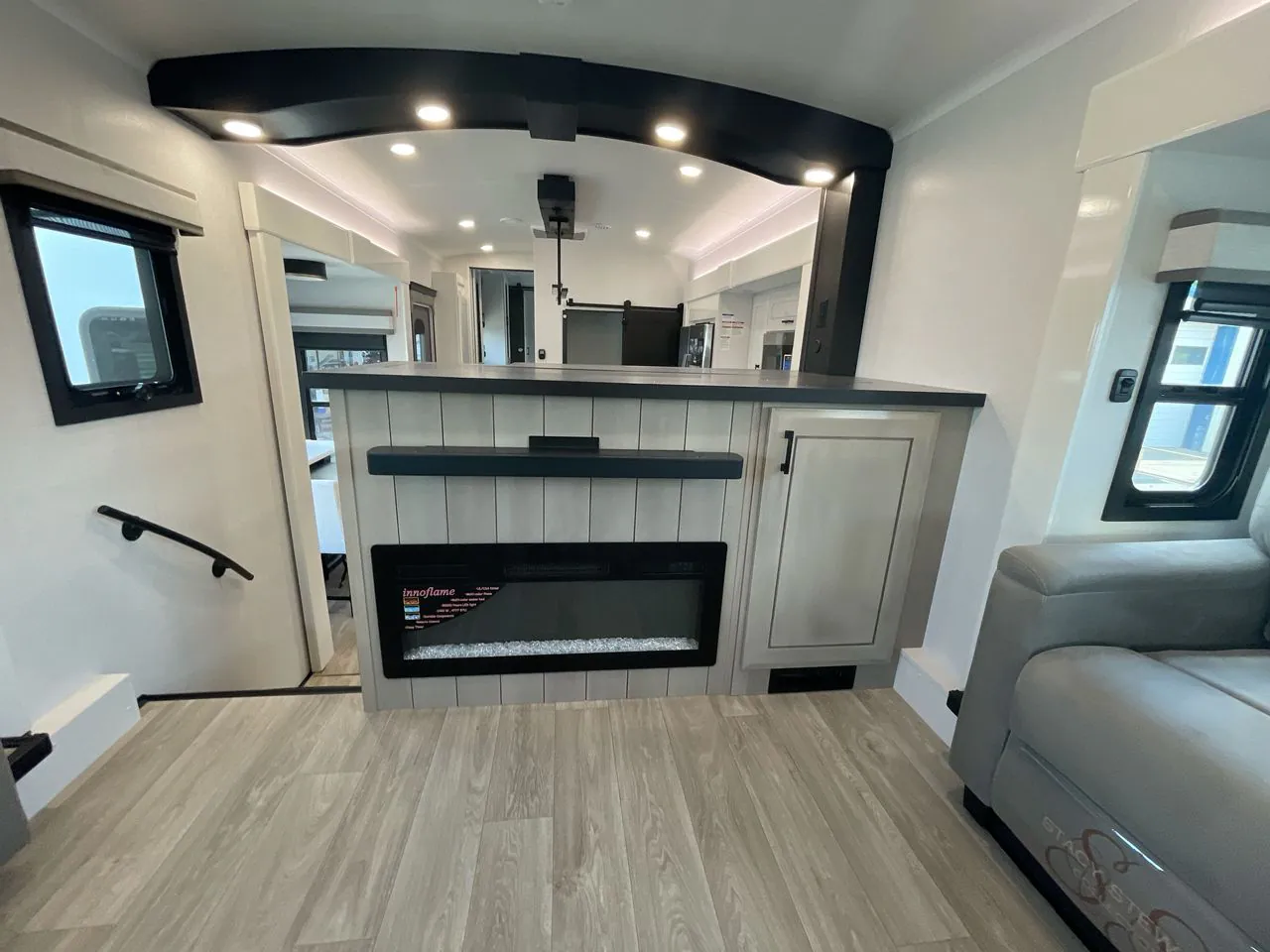 2027 Jayco Pinnacle 39FLOK — Living area fireplace and television wall with cabinet storage, stairway, and a nearby sofa edge