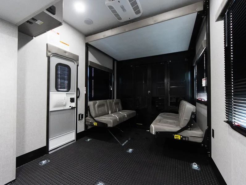 2025 Jayco Seismic Luxury Series 4113 — Toy-hauler garage with rubberized cargo floor, opposing bench seats, tie-down rings, and dark storage cabinets