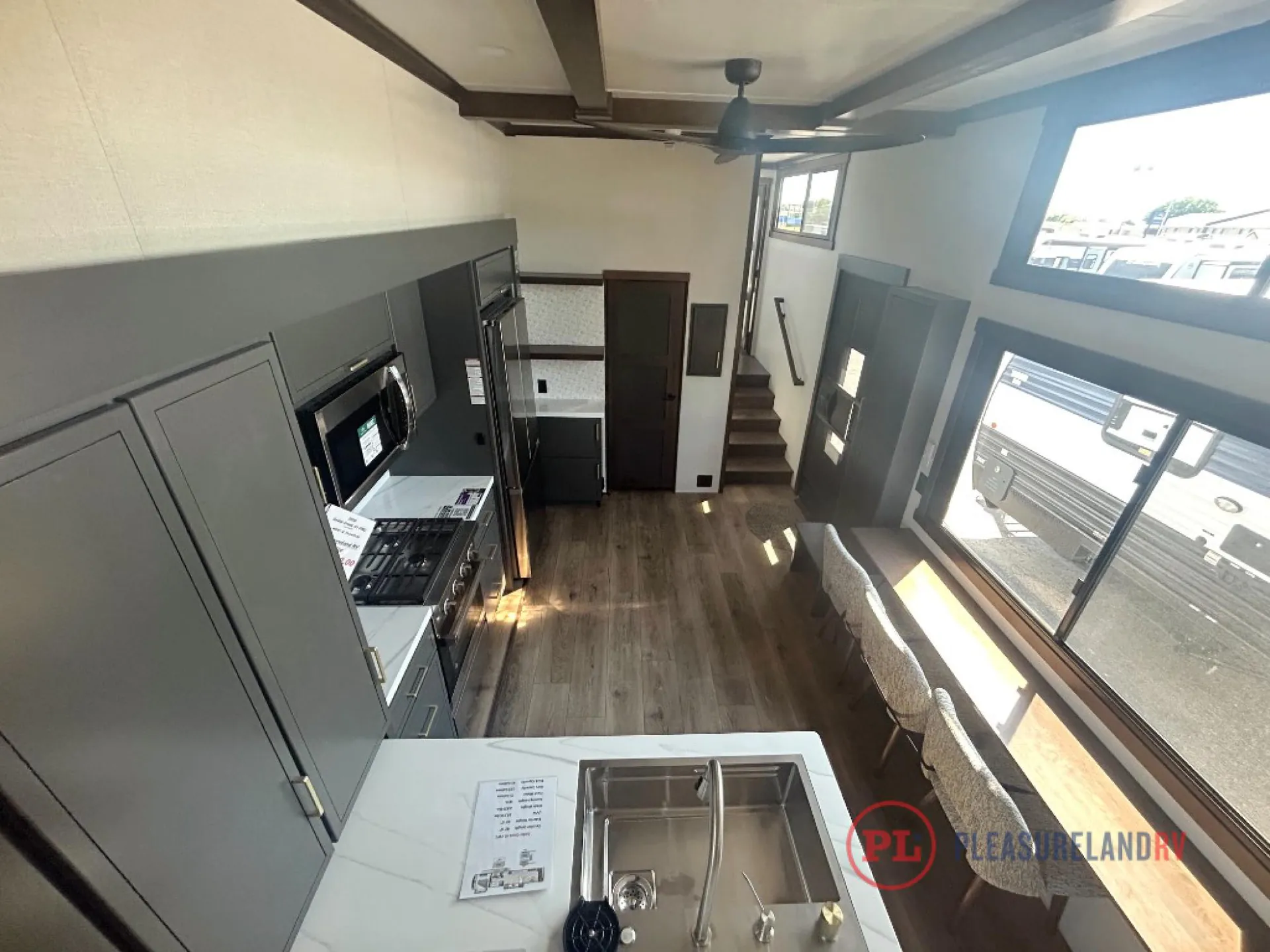 2026 Forest River Cedar Creek Cottage 41FWC — Fifth wheel kitchen island with sink, range, refrigerator, adjacent dining counter, stairs, and overhead sleeping platform