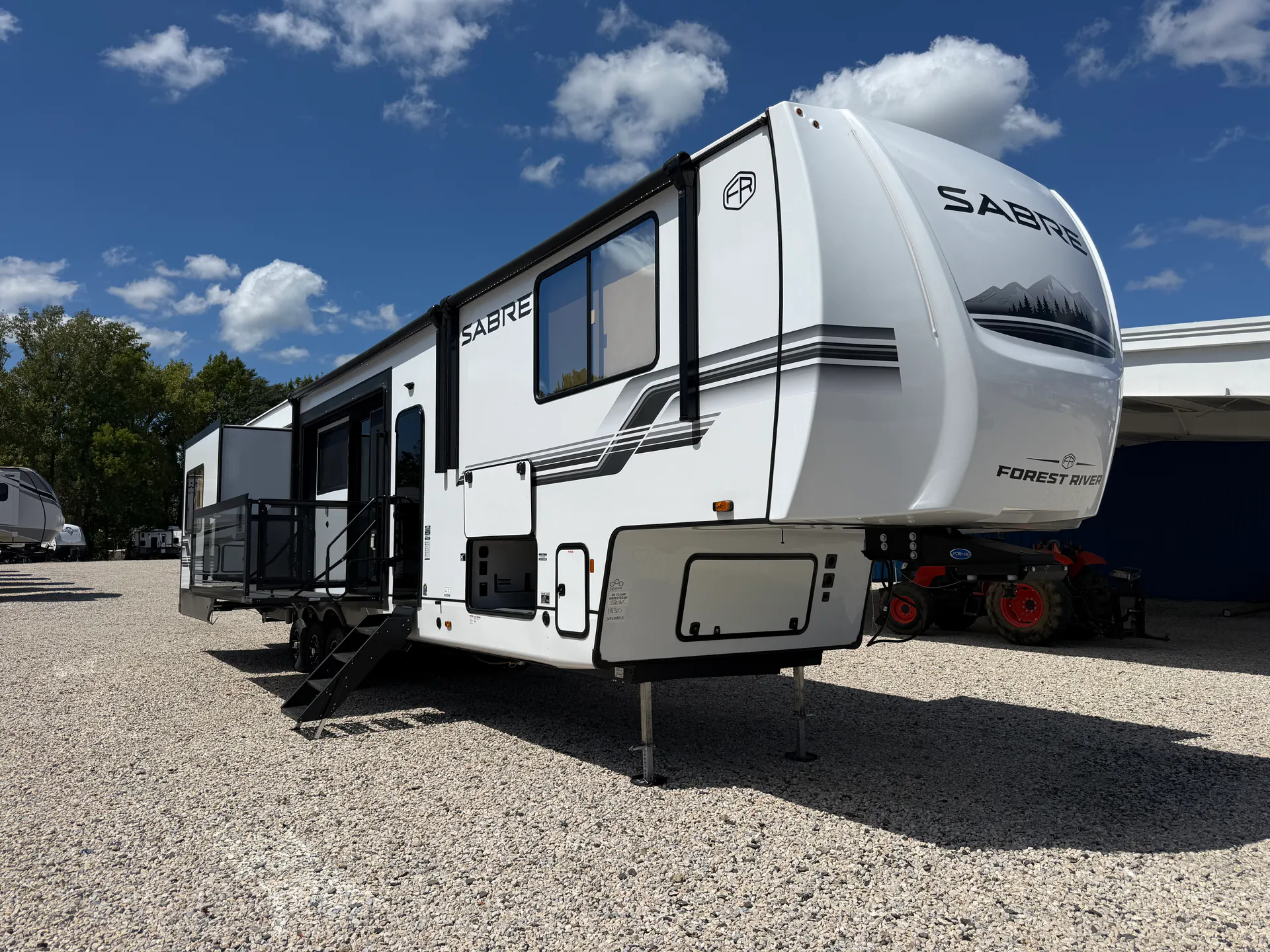 2027 Forest River Sabre 38RVHUNTER — The full exterior front and side of a Sabre fifth-wheel RV, including shell, hitch area, steps, and slide-outs