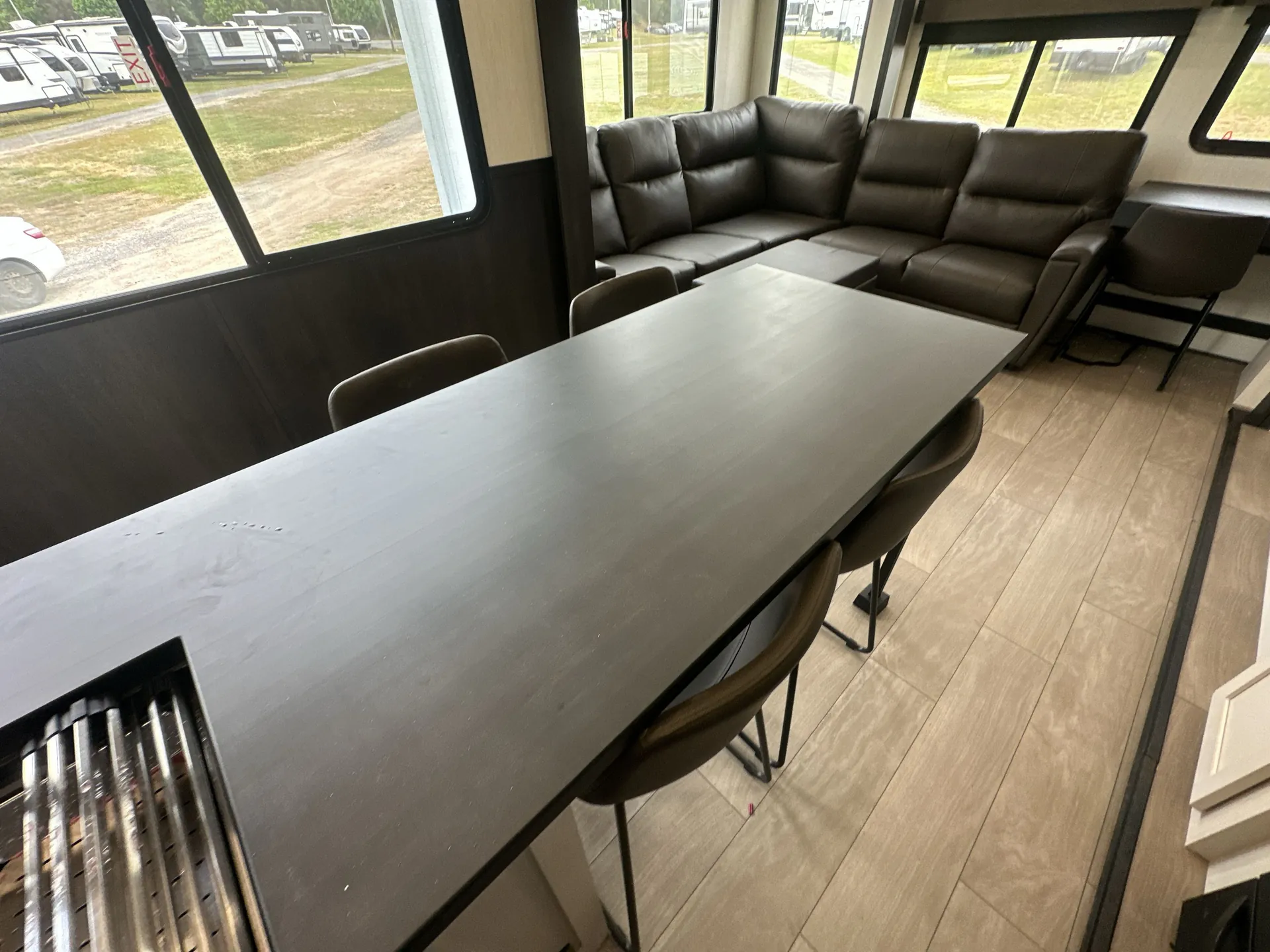 2026 Forest River Arctic Wolf 38LEAH.G — Freestanding dining table with chairs fills the foreground beside a sectional lounge and windows