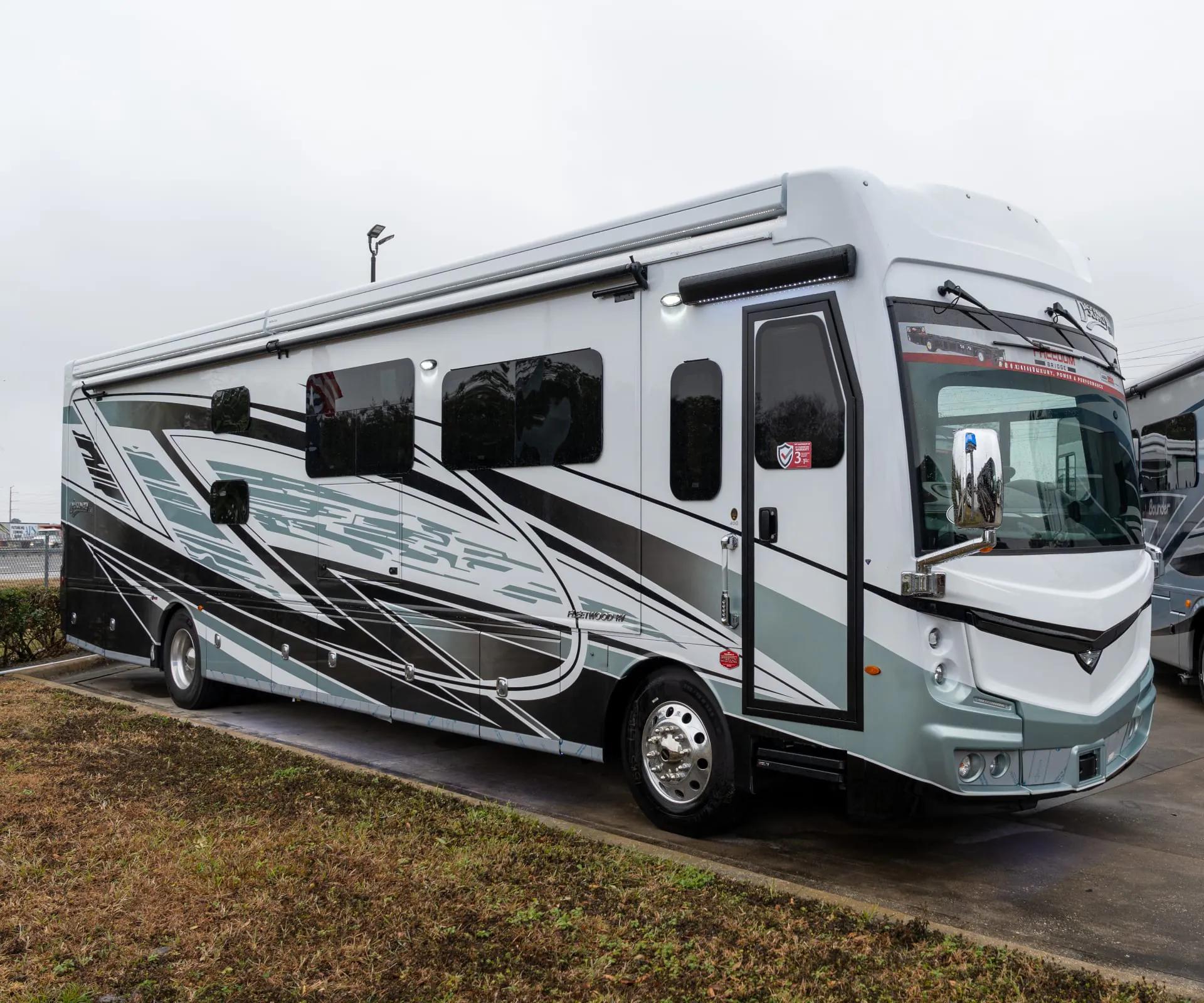 2026 Fleetwood Discovery LXE 40G — The outside shell, front, side, windows, awning, wheels, and exterior graphics of a motorhome