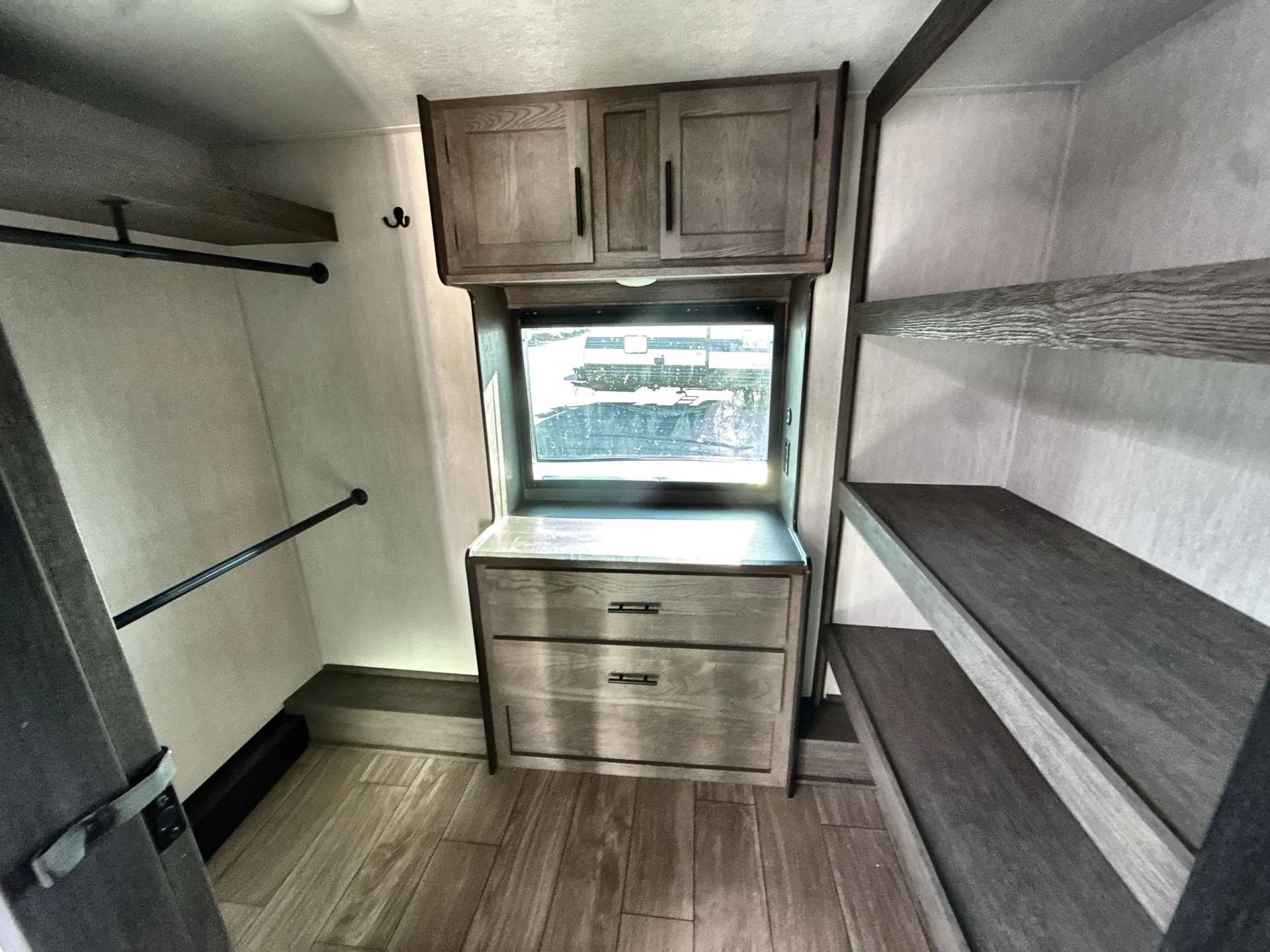 2026 Forest River Arctic Wolf 38LEAH.G — Bedroom storage wall with dresser, overhead cabinet, open hanging closet, and shelving beside a window