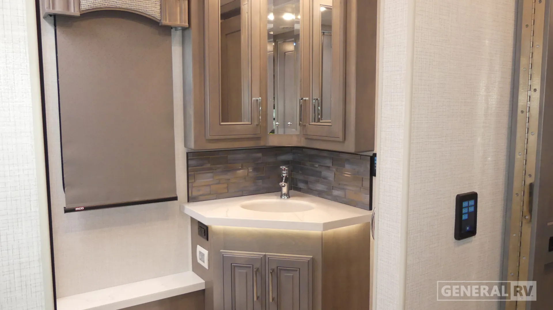 2026 Fleetwood Discovery LXE 40G — Corner bathroom vanity with sink, mirrored cabinets, backsplash, and adjacent window shade