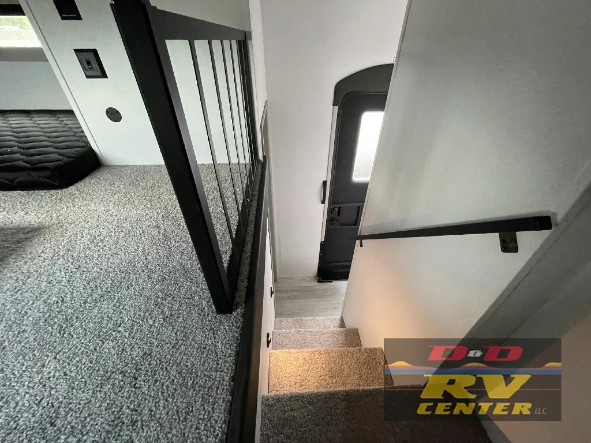 2026 Keystone Montana High Country 377FL — Over-cab loft mattress beside a carpeted landing and stairs leading to the fifth-wheel entry door