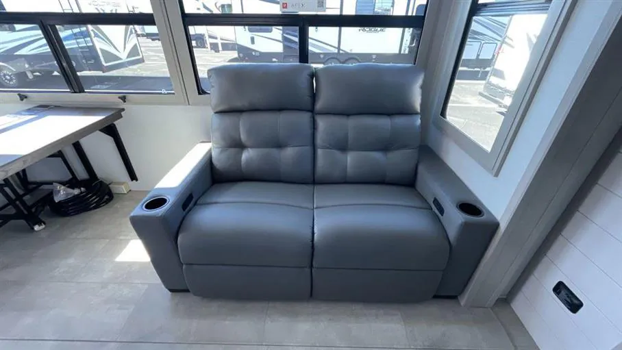 2026 Grand Design Solitude 391DL — Close view of a dual reclining lounge sofa with integrated cup holders beside the dinette