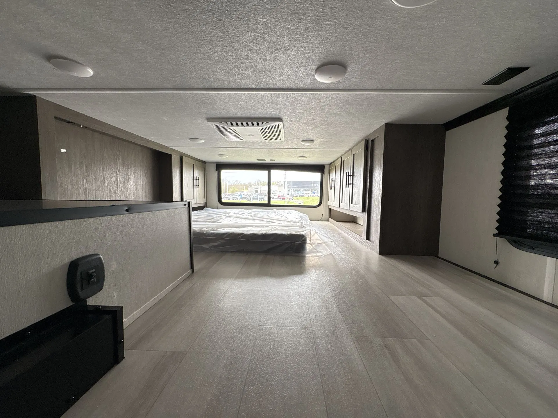 2026 Forest River Cherokee Wolf Pack 397STAY — Main bedroom contains a bed, surrounding overhead cabinets, side wardrobes, and a wide rear window