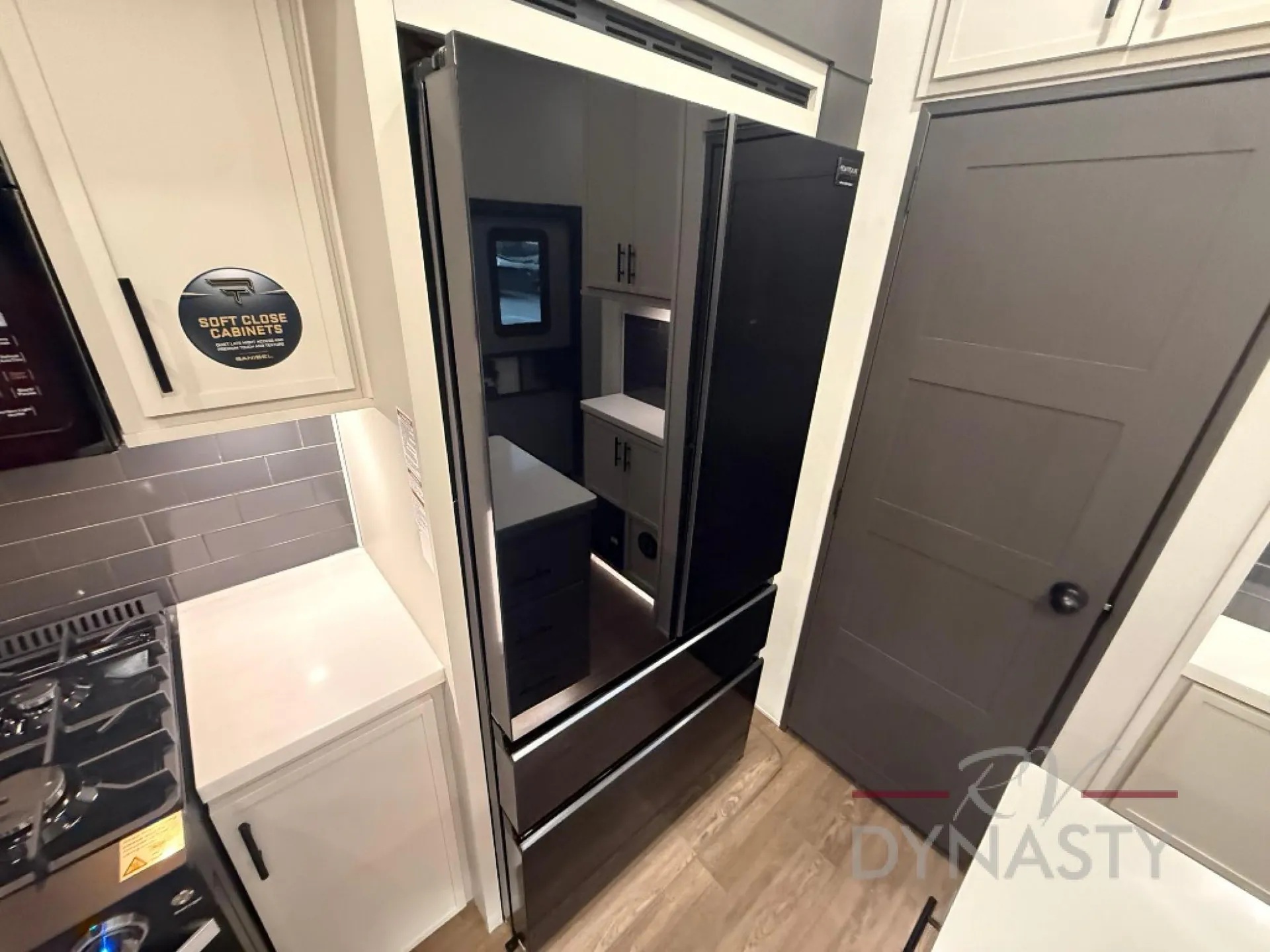 2027 Forest River Sanibel 40BUNK — Kitchen refrigerator beside a gas range, countertop, backsplash, and surrounding cabinetry in a fifth wheel trailer