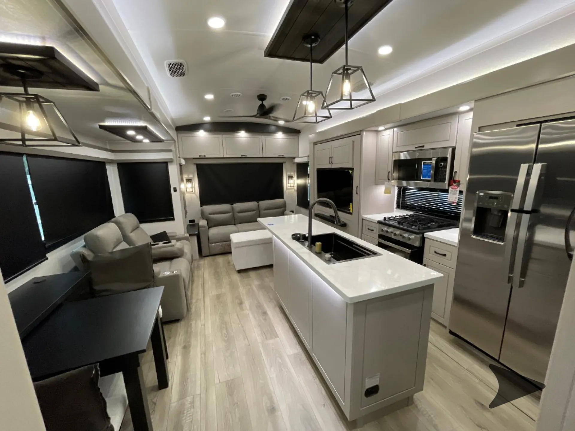 2026 Jayco North Point 377RLBH — Fifth-wheel interior overview with central kitchen island, gas range, refrigerator, lounge seating, and dining table
