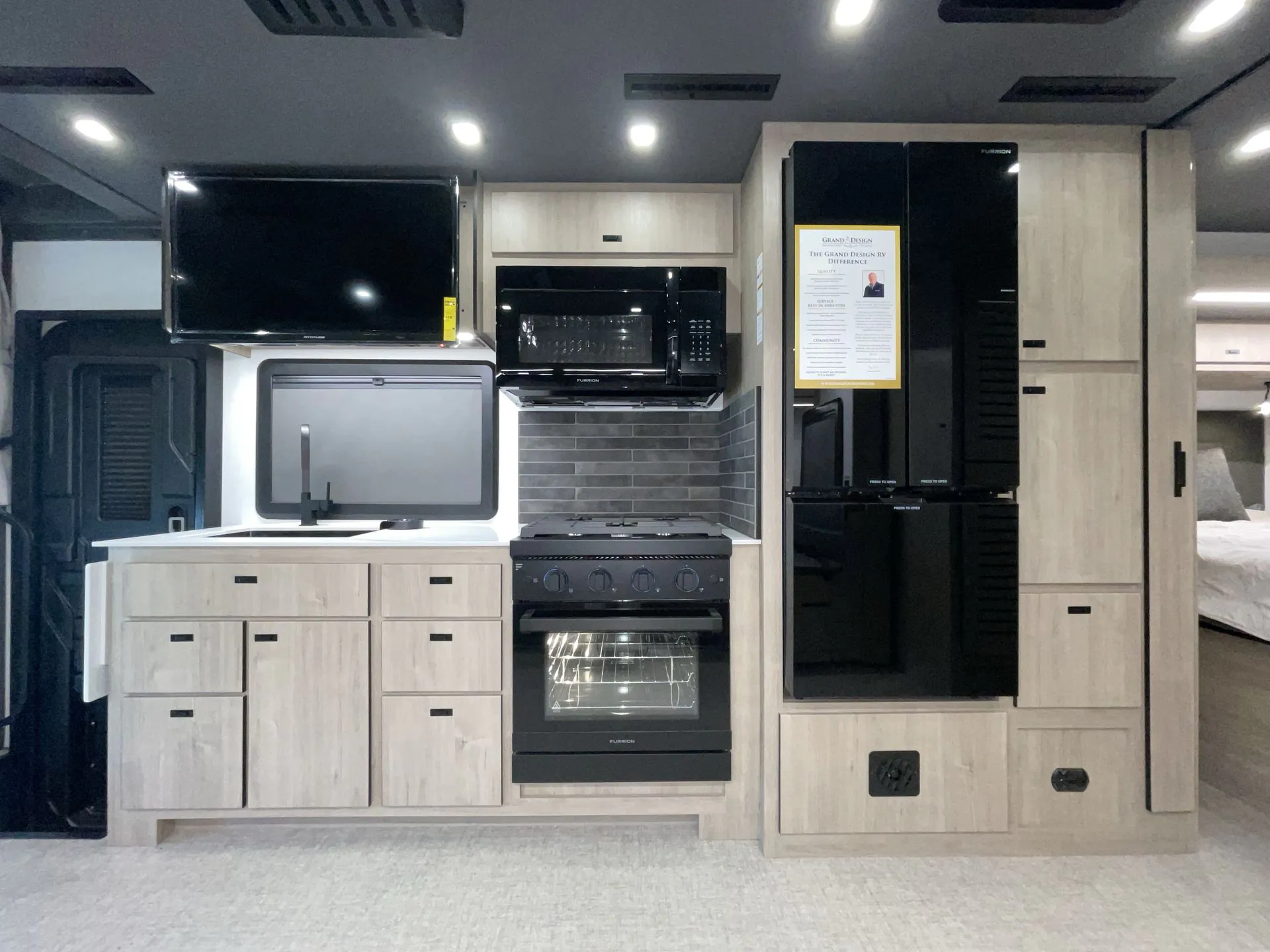 2027 Grand Design Lineage Series F 31ZW — Motorhome kitchen wall with sink, microwave, gas range, oven, refrigerator, backsplash, and surrounding cabinetry