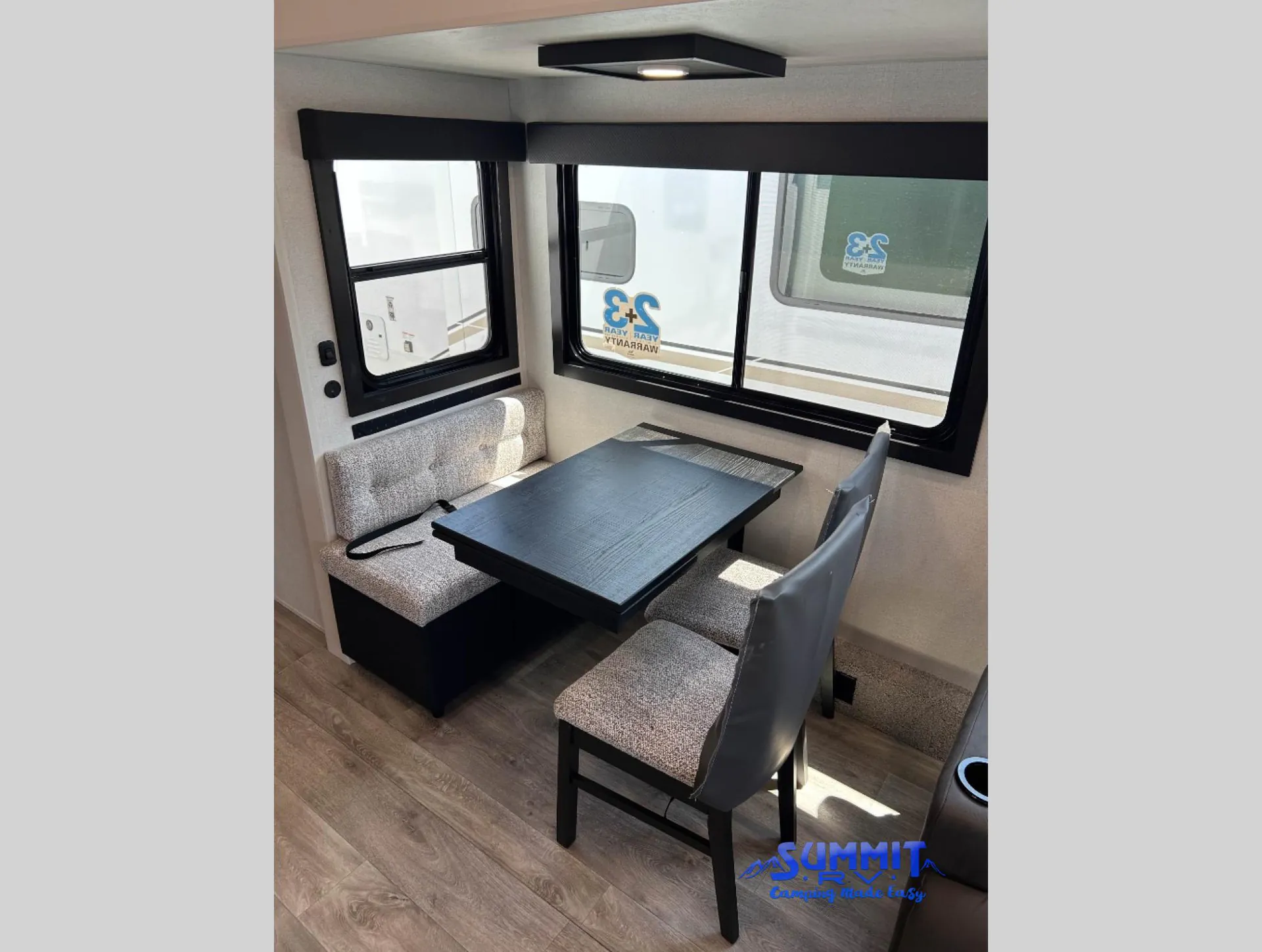 2027 Jayco Eagle 355MBQS — Fifth wheel dinette with booth seating, two chairs, and a rectangular table beside large windows