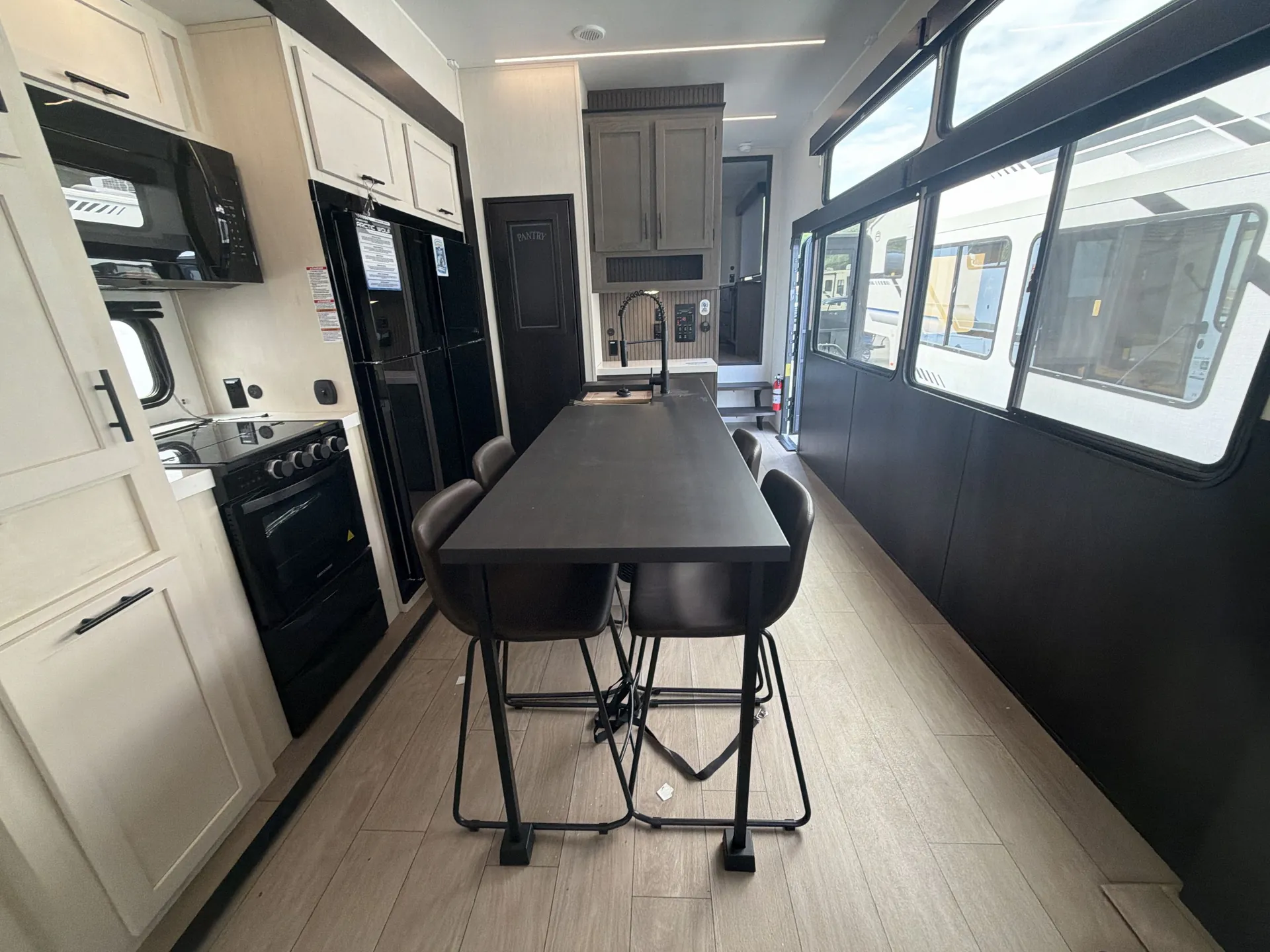 2026 Forest River Arctic Wolf 38LEAH.G — Fifth wheel dining table and chairs beside kitchen range, refrigerator, counters, and sink
