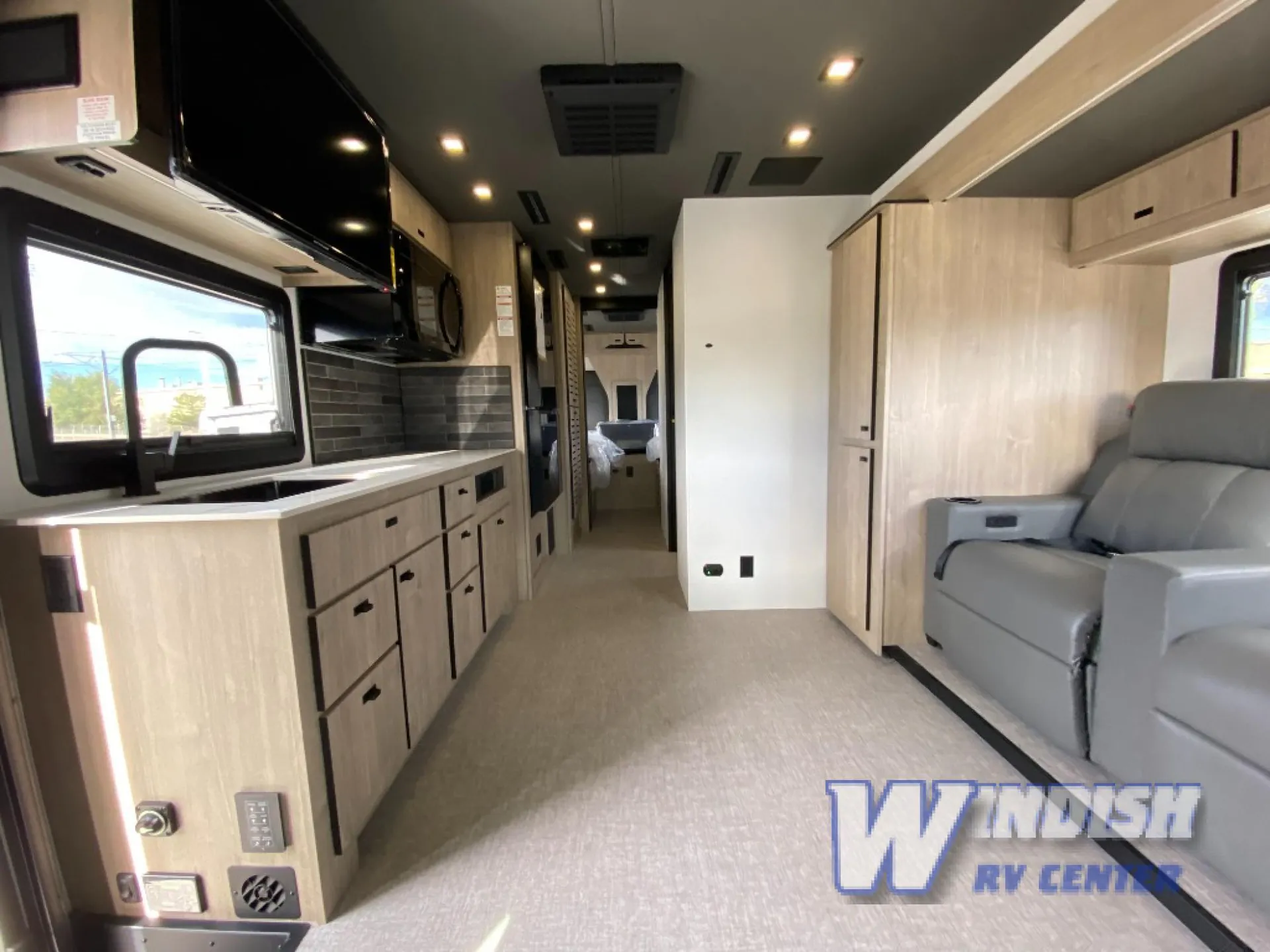 2027 Grand Design Lineage Series F 29AN5 — Motorhome overview with a full kitchen on the left, recliner seating on the right, and a bed visible down the hallway