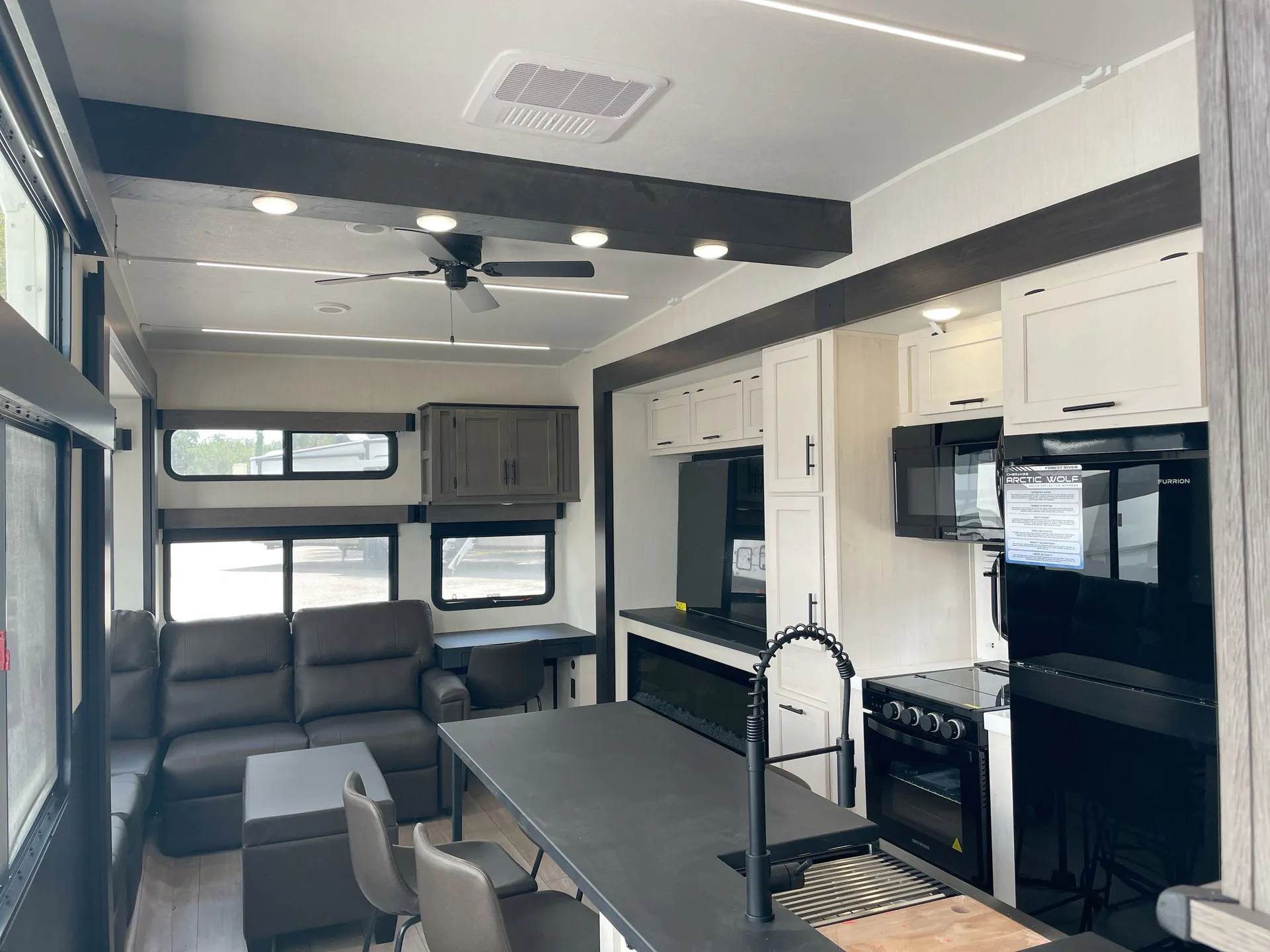 2026 Forest River Arctic Wolf 38LEAH.G — Fifth wheel interior overview with a kitchen island, dining chairs, refrigerator, range, and lounge seating by large windows