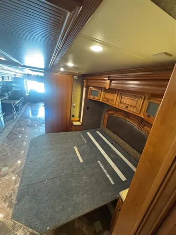 2016 Newmar Dutch Star 4369 — Main bedroom showing the upholstered bed platform, decorative headboard, overhead cabinets, and surrounding wood cabinetry