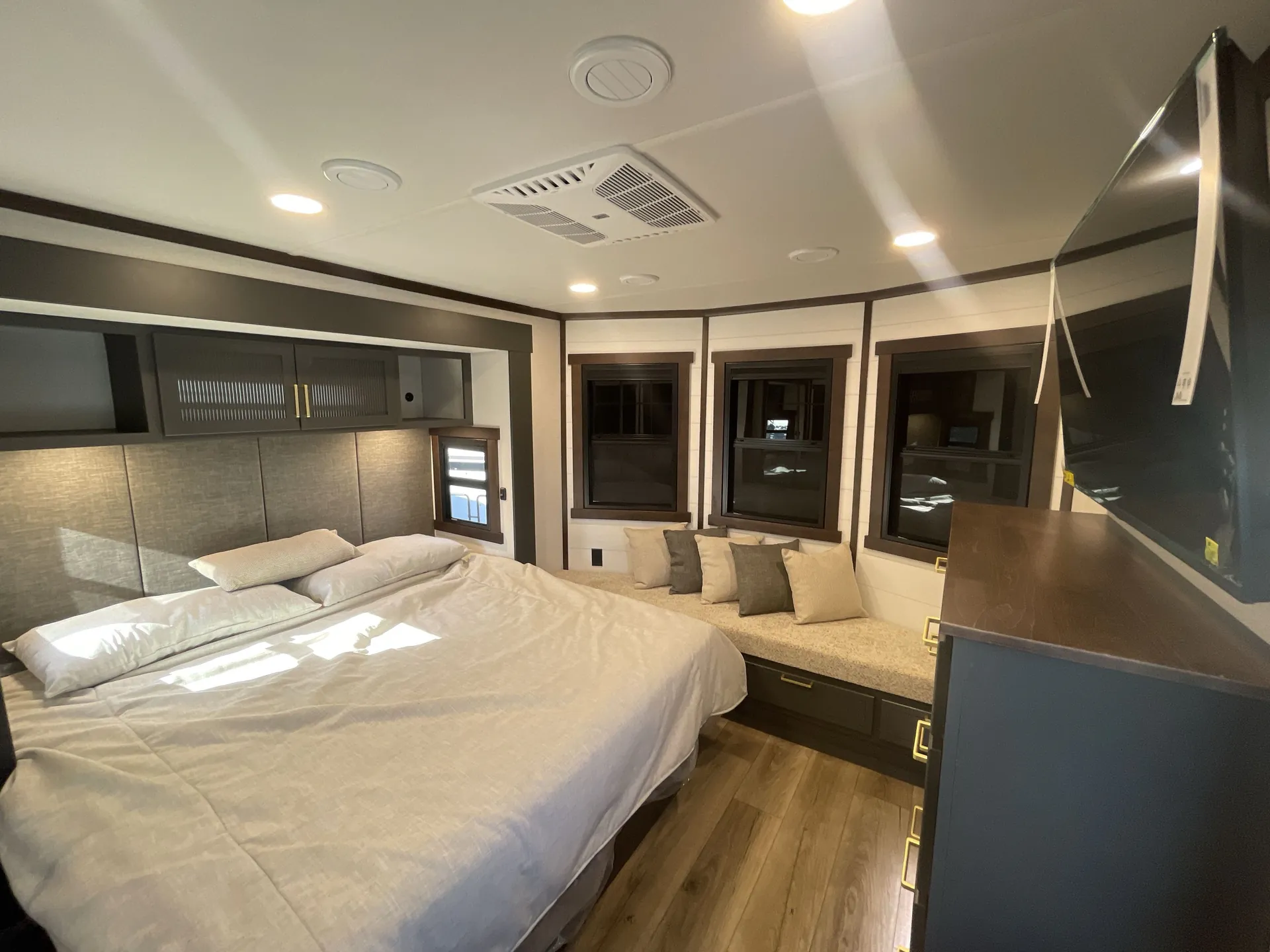 2026 Forest River Cedar Creek Cottage 41FWC — Enclosed bedroom with a made bed, overhead cabinets, windows, and upholstered storage bench