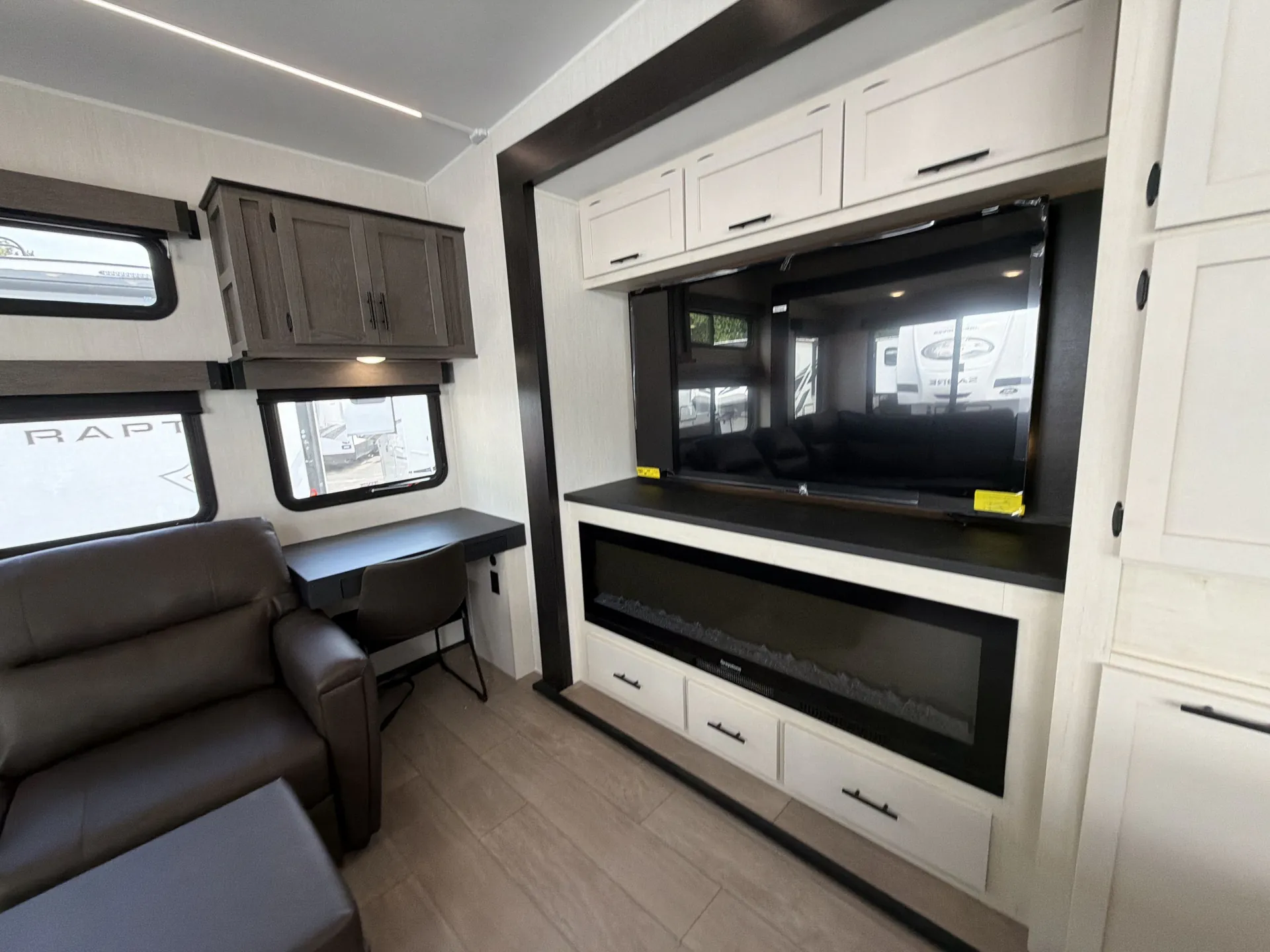 2026 Forest River Arctic Wolf 38LEAH.G — Fifth wheel living area with recliner, desk chair, television, fireplace, and surrounding cabinetry