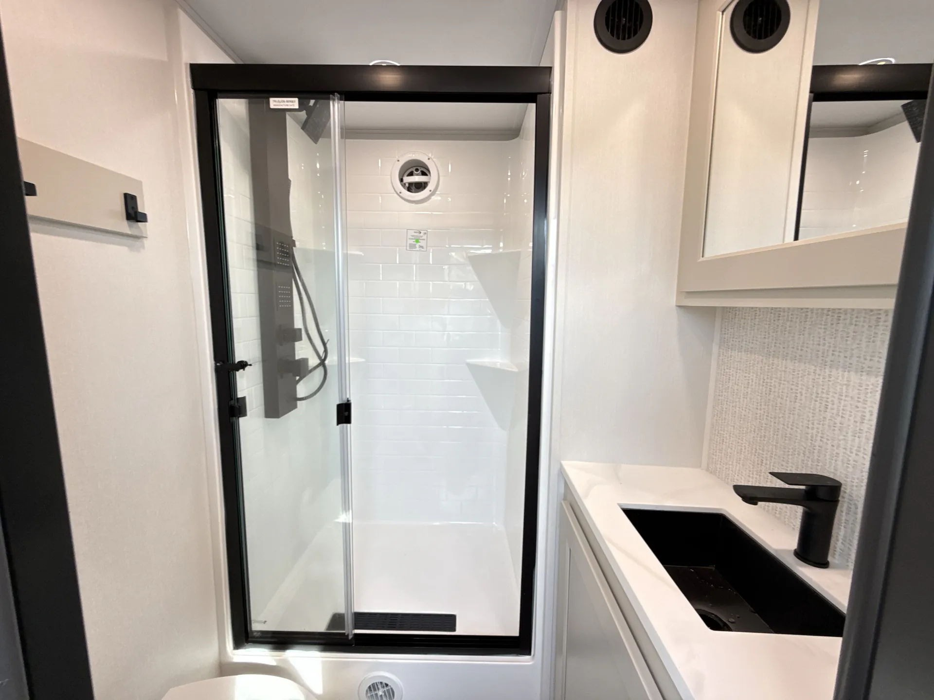 2026 Grand Design Foundation 42GD — Bathroom view centered on a glass shower with a toilet, vanity sink, shelves, and vent