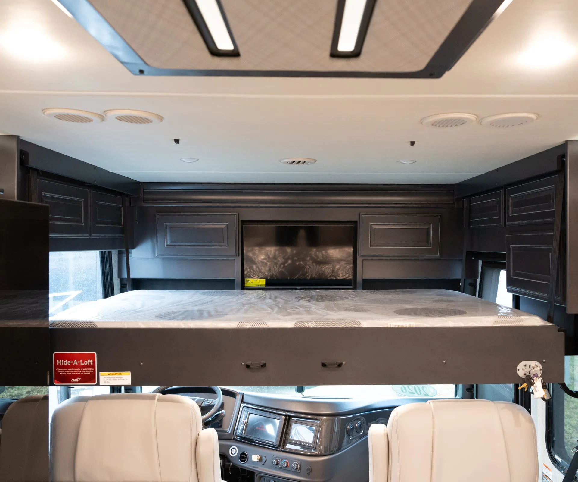 2026 Fleetwood Discovery LXE 40G — Over-cab loft mattress with surrounding storage cabinets above the visible Class A dashboard