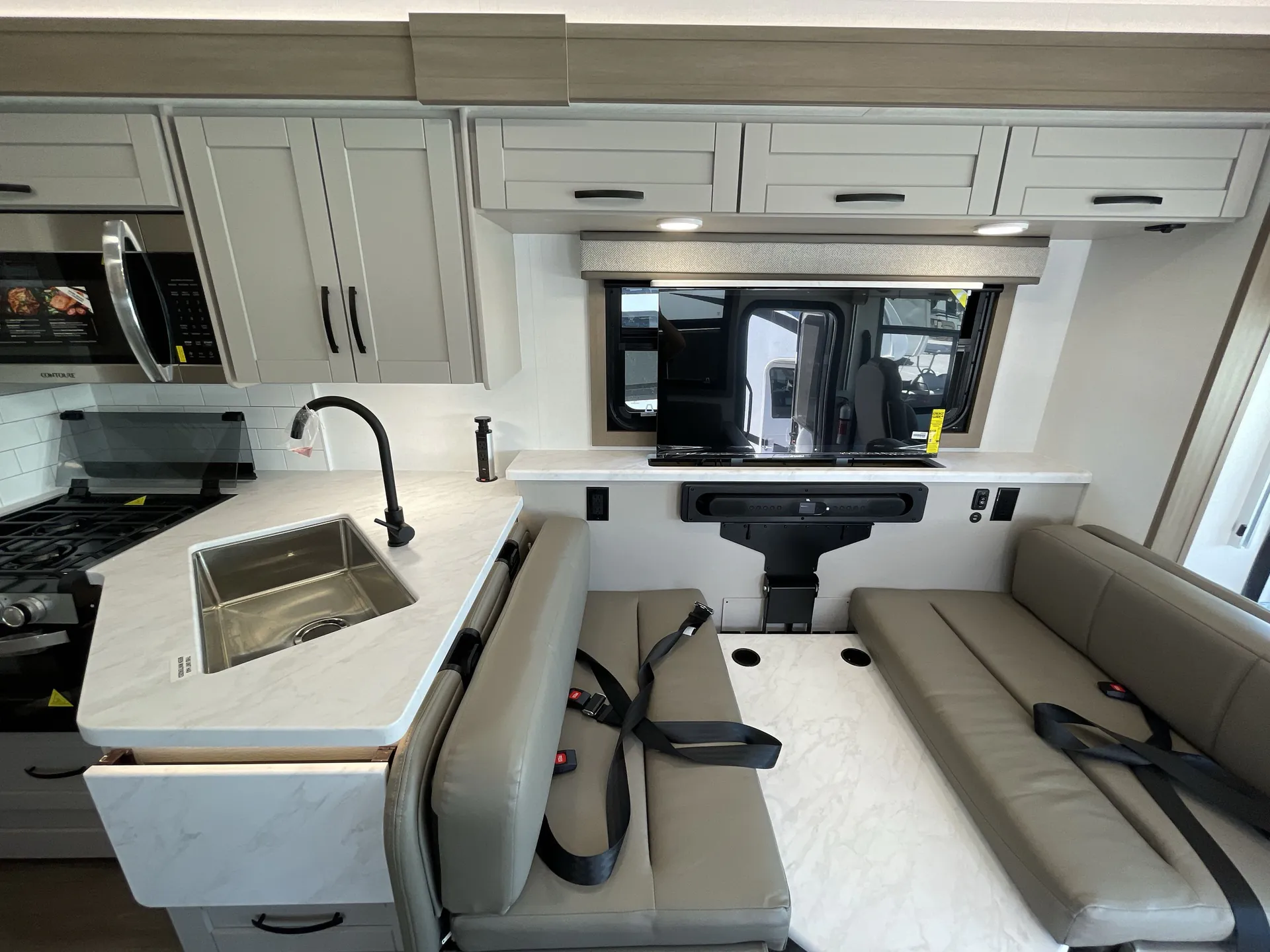2027 Jayco Alante 29F — Dinette with seat belts beside the kitchen sink and range, facing the motorhome cockpit