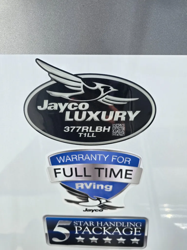 2026 Jayco North Point 377RLBH — Close-up photograph of manufacturer and warranty decals on the RV exterior; no distinct functional category is shown