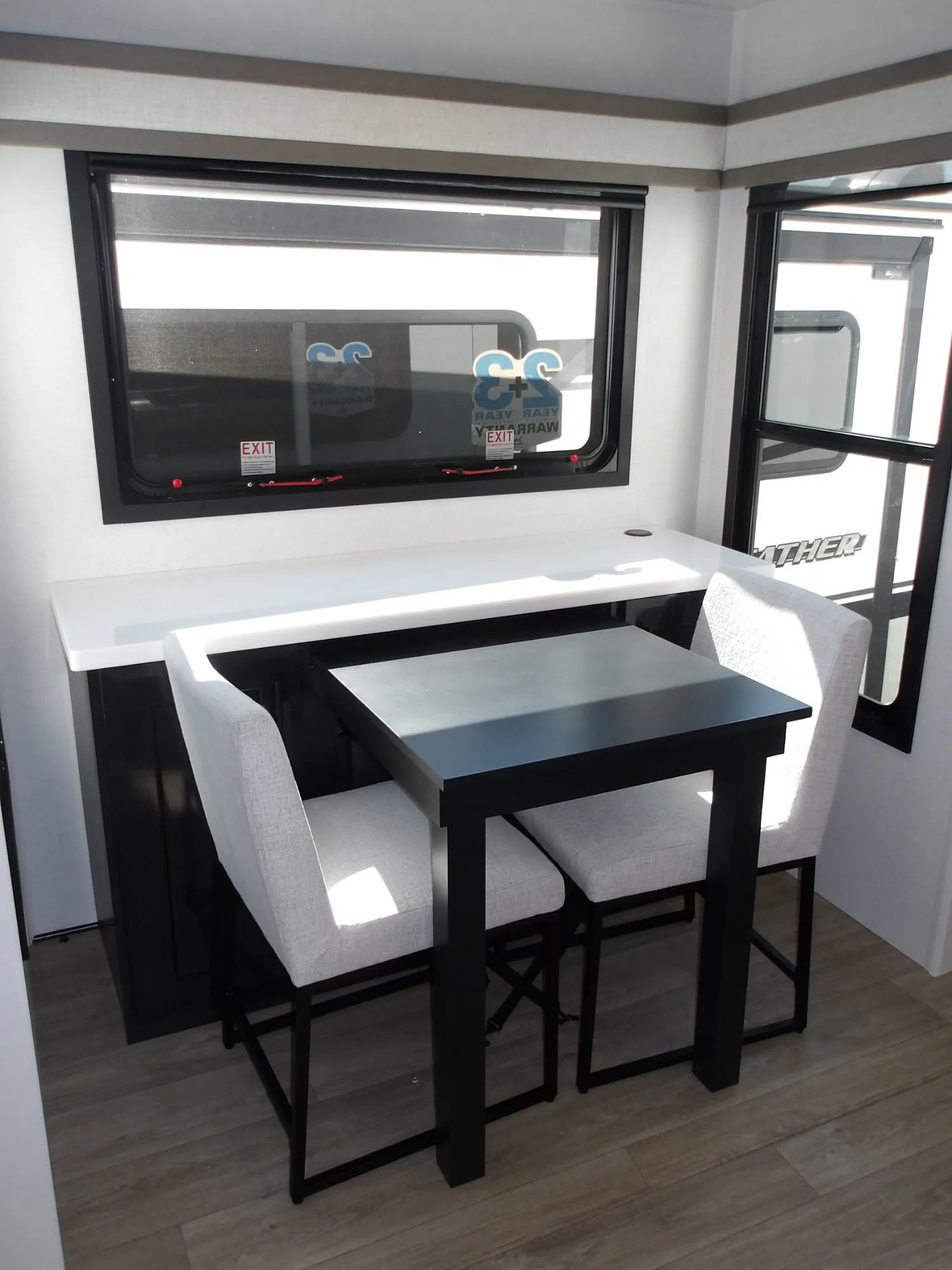 2027 Jayco Pinnacle 39FLOK — Freestanding dining table with four upholstered chairs beside a window and rear countertop
