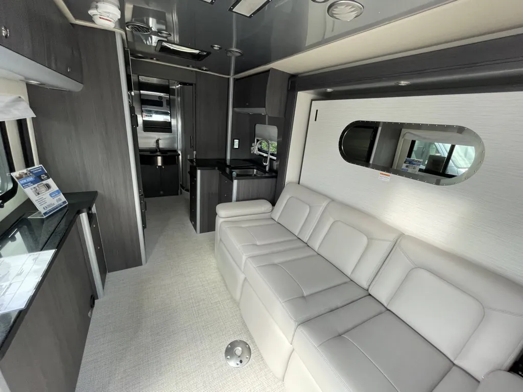 2026 Airstream Atlas Murphy Suite — Class B van lounge with a large sofa, galley sink and cabinetry visible along the aisle