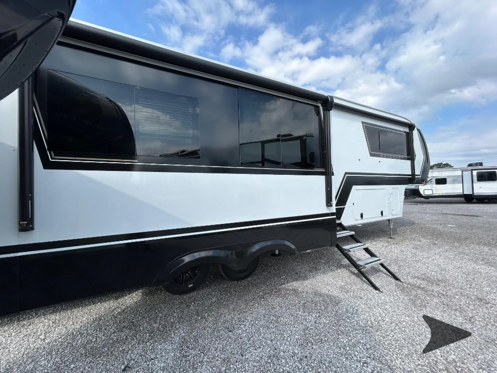 2026 Brinkley Model Z 3515 — Exterior side photograph showing the RV shell, awning, windows, wheels, entry steps, and exterior storage