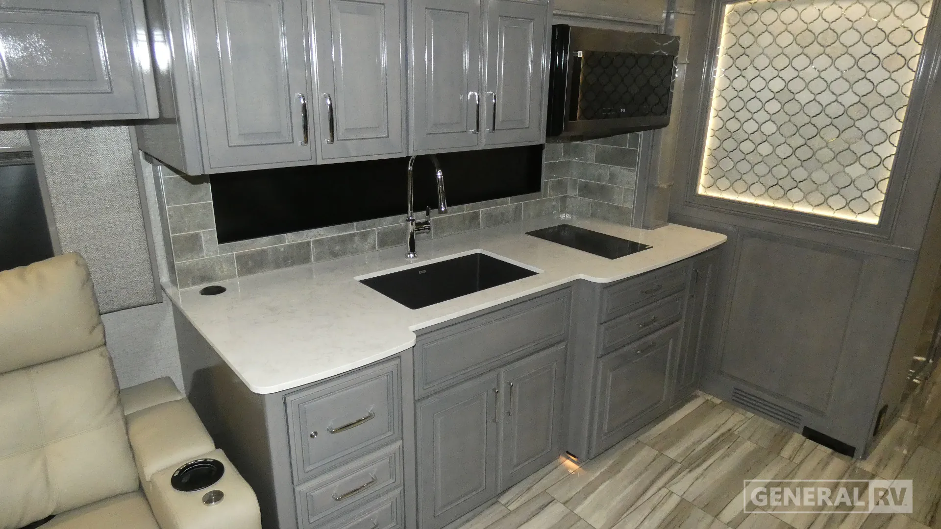 2026 American Coach American Dream 45A — Kitchen with dual sinks, faucet, countertop, backsplash, microwave, gray cabinetry, and an adjacent recliner