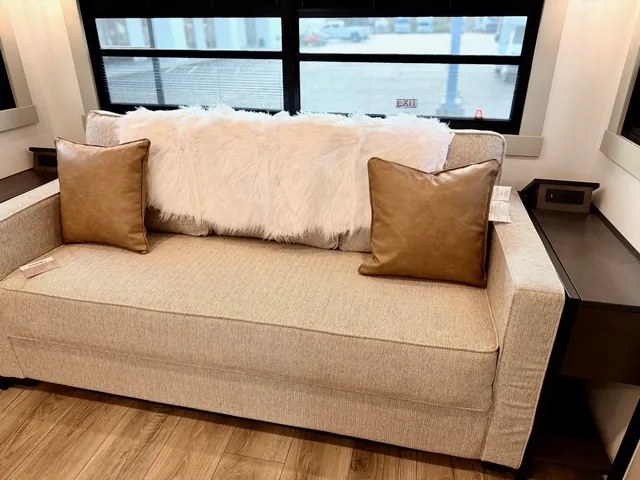 2026 Brinkley Model Z 3610 — Living room sofa with two leather pillows beneath wide windows, flanked by dark side tables and cabinetry