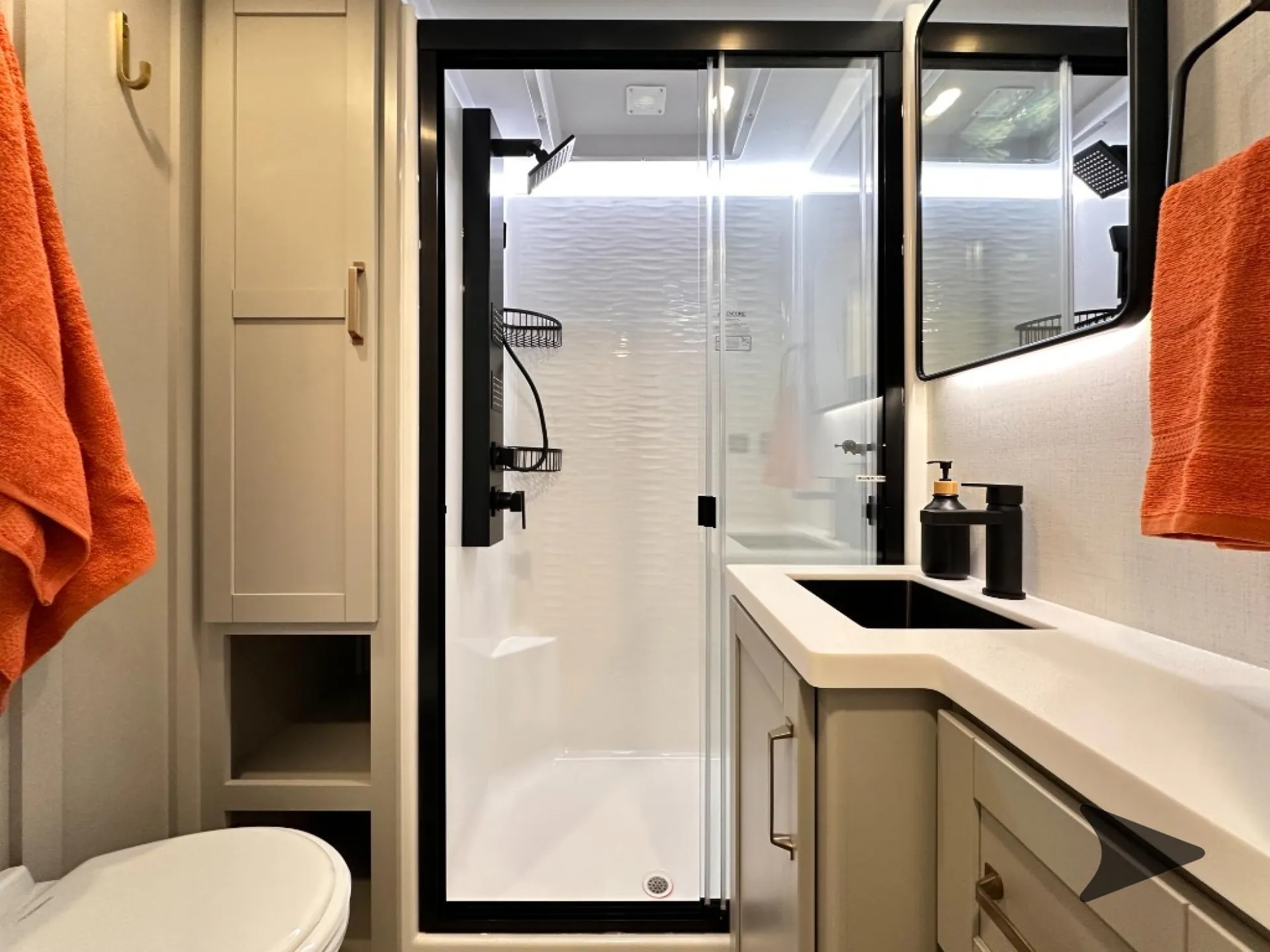 2026 Brinkley Model Z 3610 — Fifth wheel bathroom with a glass shower, toilet, vanity sink, mirrored cabinet, and orange towels