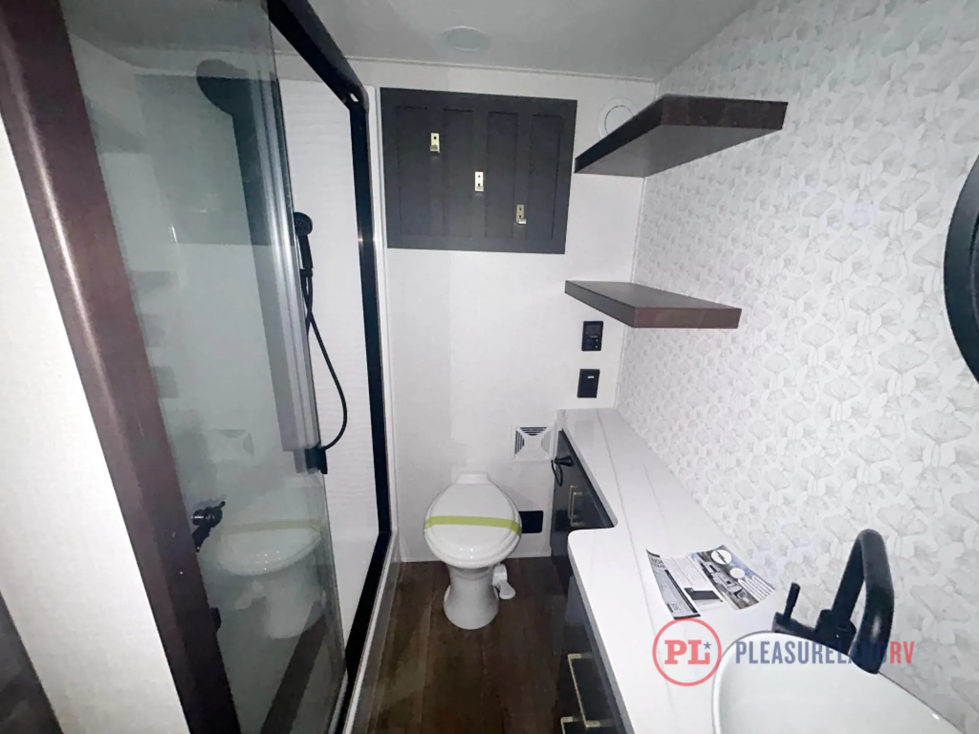 2026 Forest River Cedar Creek Cottage 41FWC — Fifth wheel bathroom with glass shower, toilet, vanity, patterned backsplash, shelves, and dark cabinetry