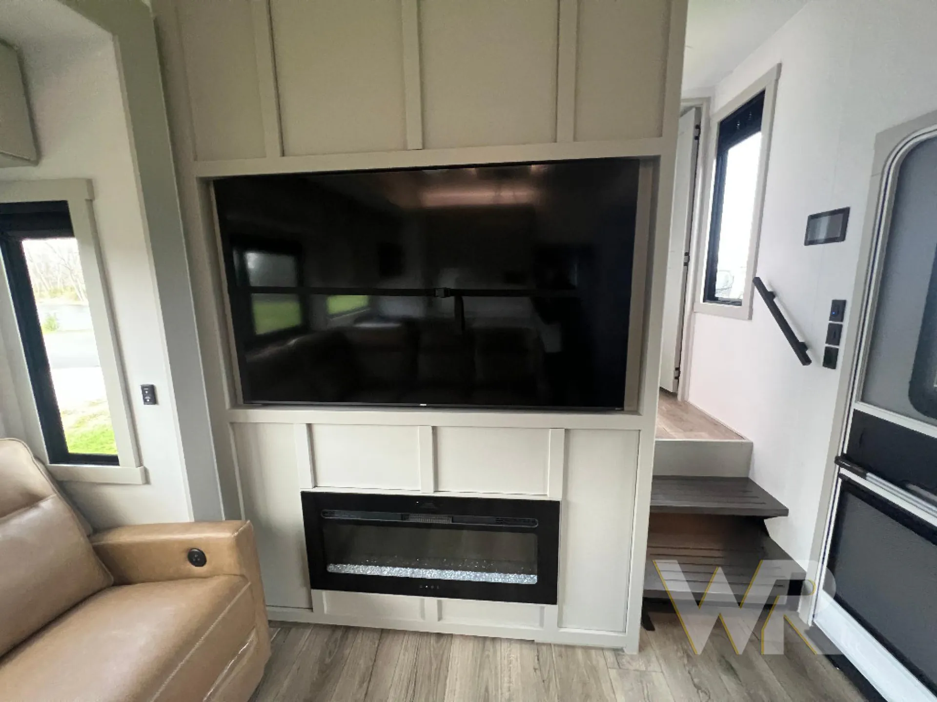 2026 Brinkley Model G 3950 — Living area entertainment wall with large television, electric fireplace, cabinetry, and adjacent recliner