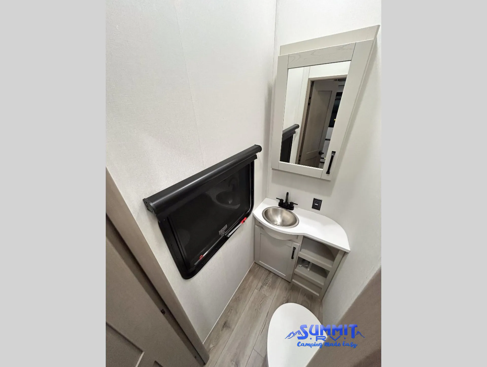 2027 Grand Design Reflection 362TBS — Compact bathroom with corner sink vanity, mirror, toilet, window, faucet, and lower storage