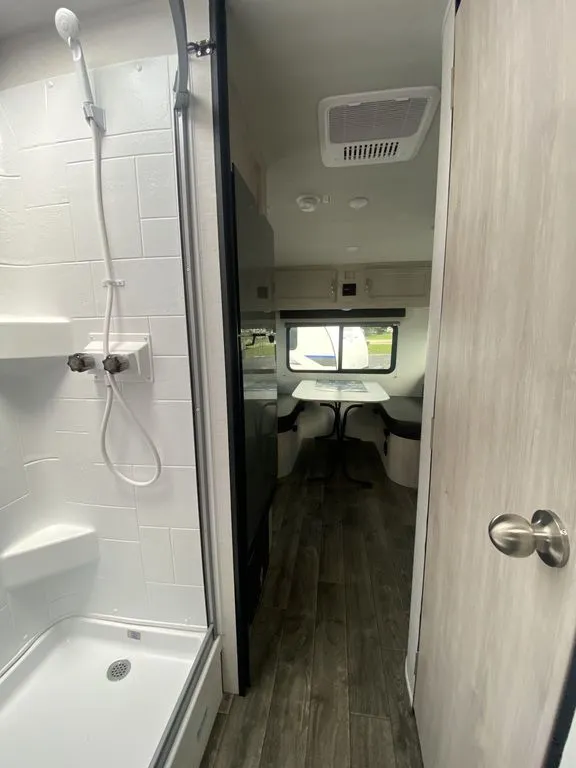 2026 Gulf Stream Vista Cruiser 19ERD — Bathroom shower in the foreground opens toward a travel trailer dinette and front window
