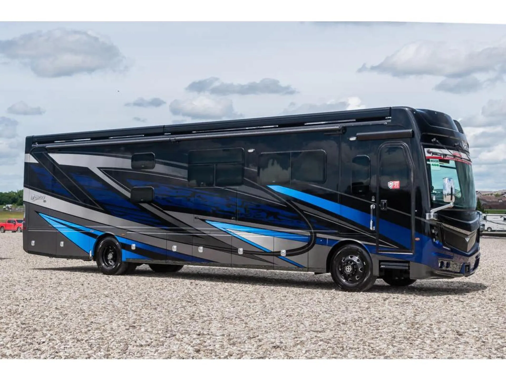 2026 Fleetwood Discovery LXE 40G — Side exterior photograph visibly shows the full motorhome body, windows, wheels, graphics, and exterior compartments