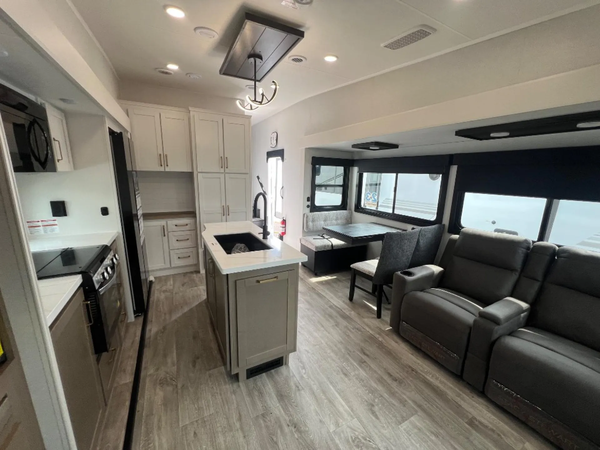 2027 Jayco Eagle 355MBQS — Reclining lounge seating faces a kitchen island, appliances, cabinetry, and adjacent dining table in an open interior