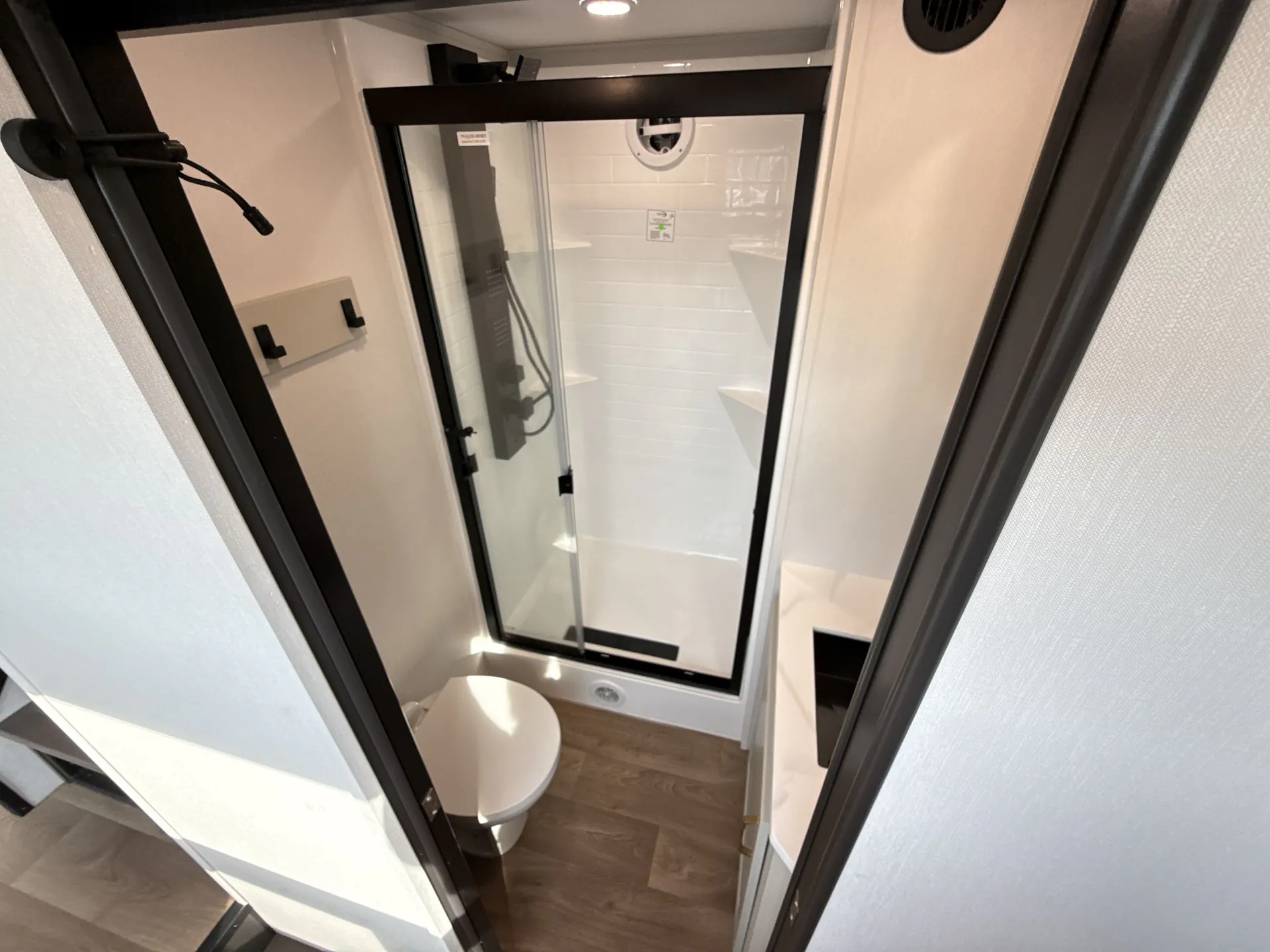 2026 Grand Design Foundation 42GD — Destination trailer bathroom with a glass shower, toilet, vanity sink, and wood-look flooring