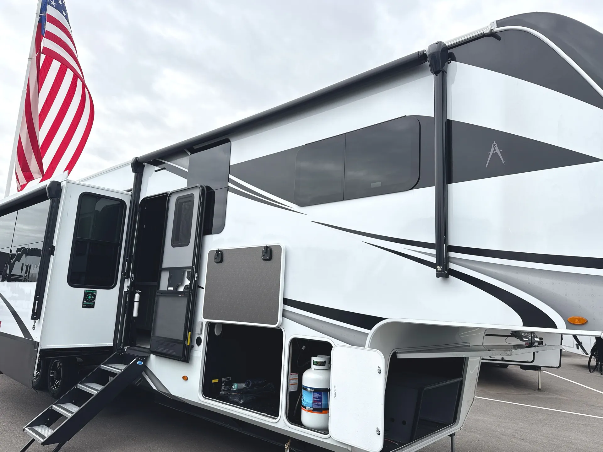 2026 Grand Design Solitude 391DL — Wide photograph of the RV exterior showing its side, slide-outs, awning, entry, and storage doors