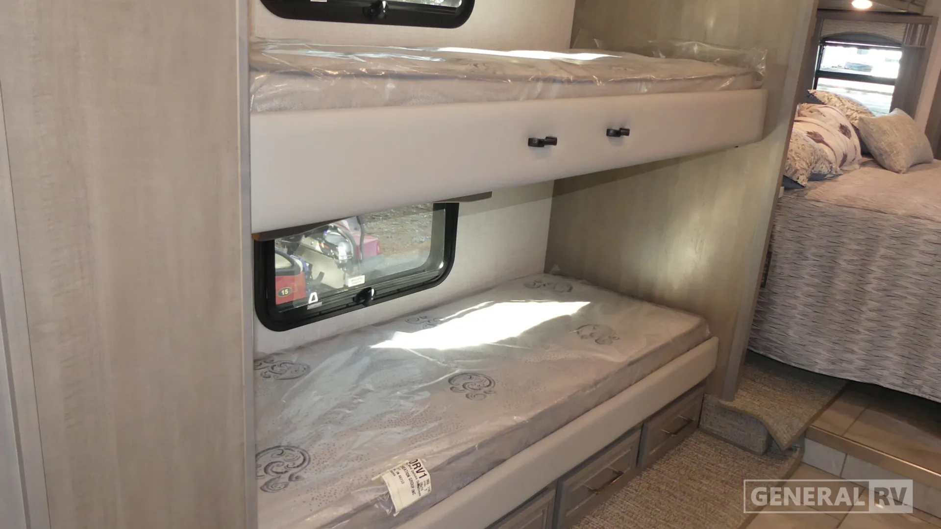 2026 Fleetwood Discovery LXE 40G — Bunk sleeping area with two mattresses, under-bed drawers, and a main bedroom bed visible beyond steps
