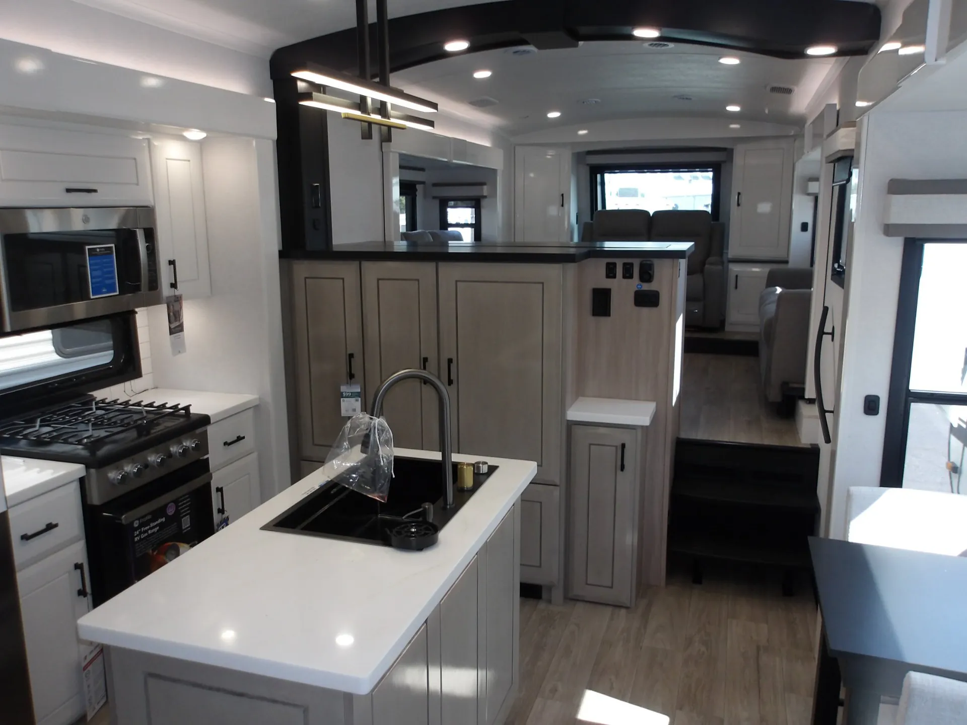 2027 Jayco Pinnacle 39FLOK — Fifth wheel kitchen with island sink, range, refrigerator, cabinetry, and lounge seating visible beyond the steps