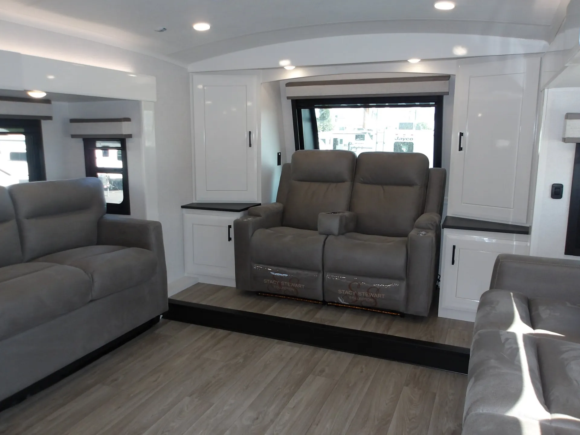 2027 Jayco Pinnacle 39FLOK — Raised fifth-wheel lounge with a central theater recliner pair, surrounding cabinets, and additional seating at the edges
